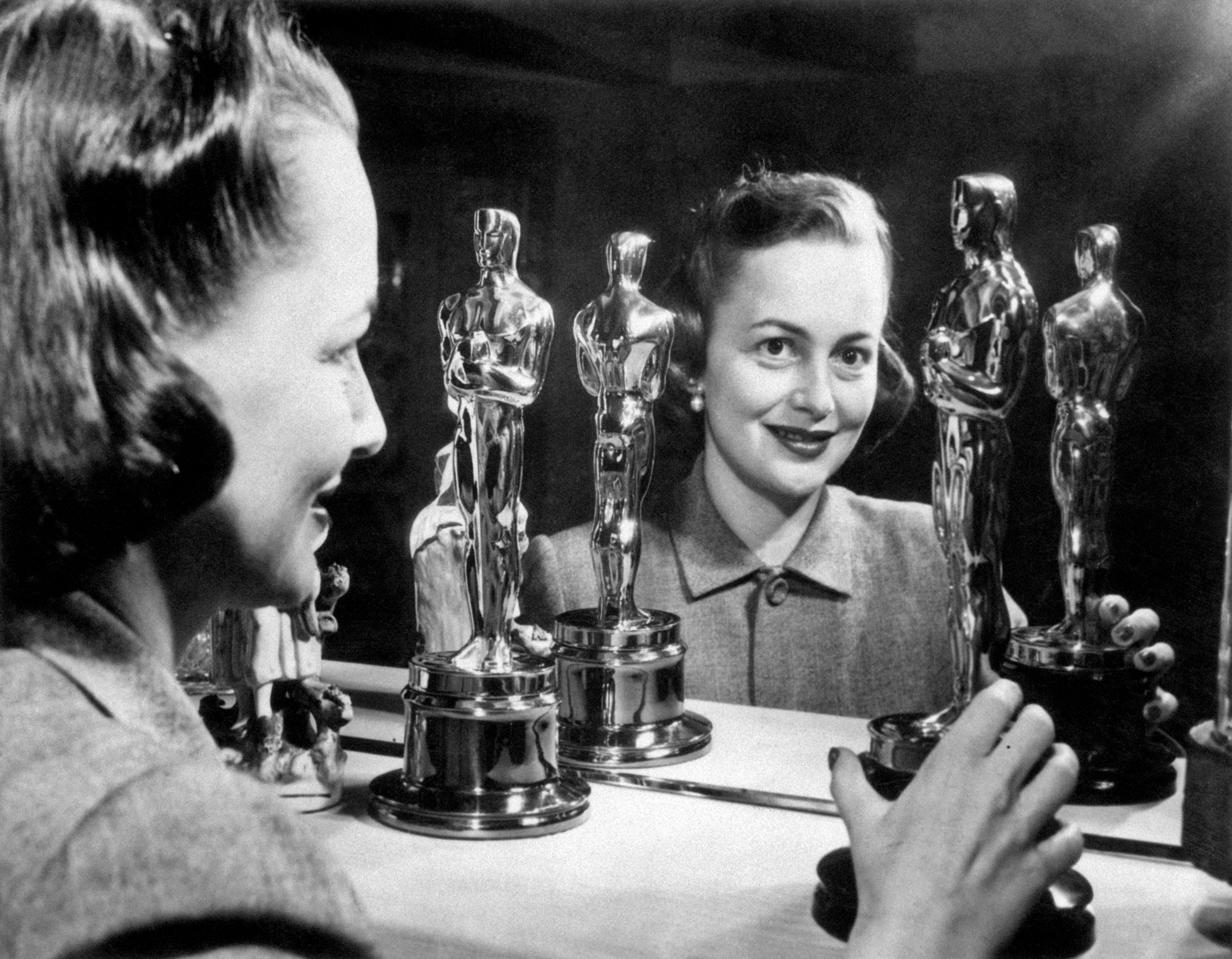 Olivia de Havilland smiling looking at her two Oscars in the 1950s. (Mondadori Portfolio—Mondadori/Getty Images)