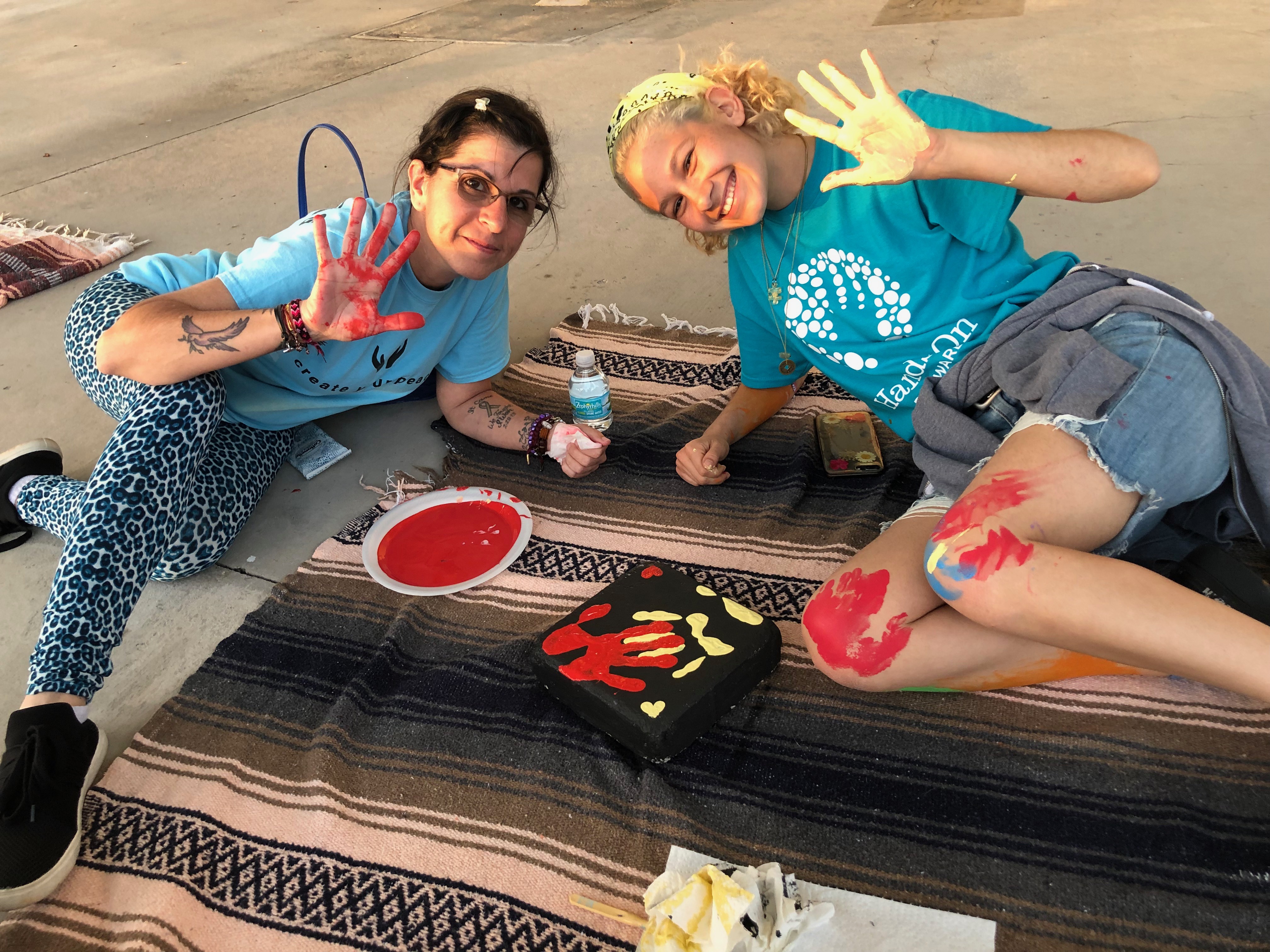 Stoneman Douglas teacher Ronit Reoven (left) and senior Tori Gonzalez (right) paint ceramic tiles for Project Grow Love, a garden memorial they built outside the school. (Courtesy of Ronit Reoven)