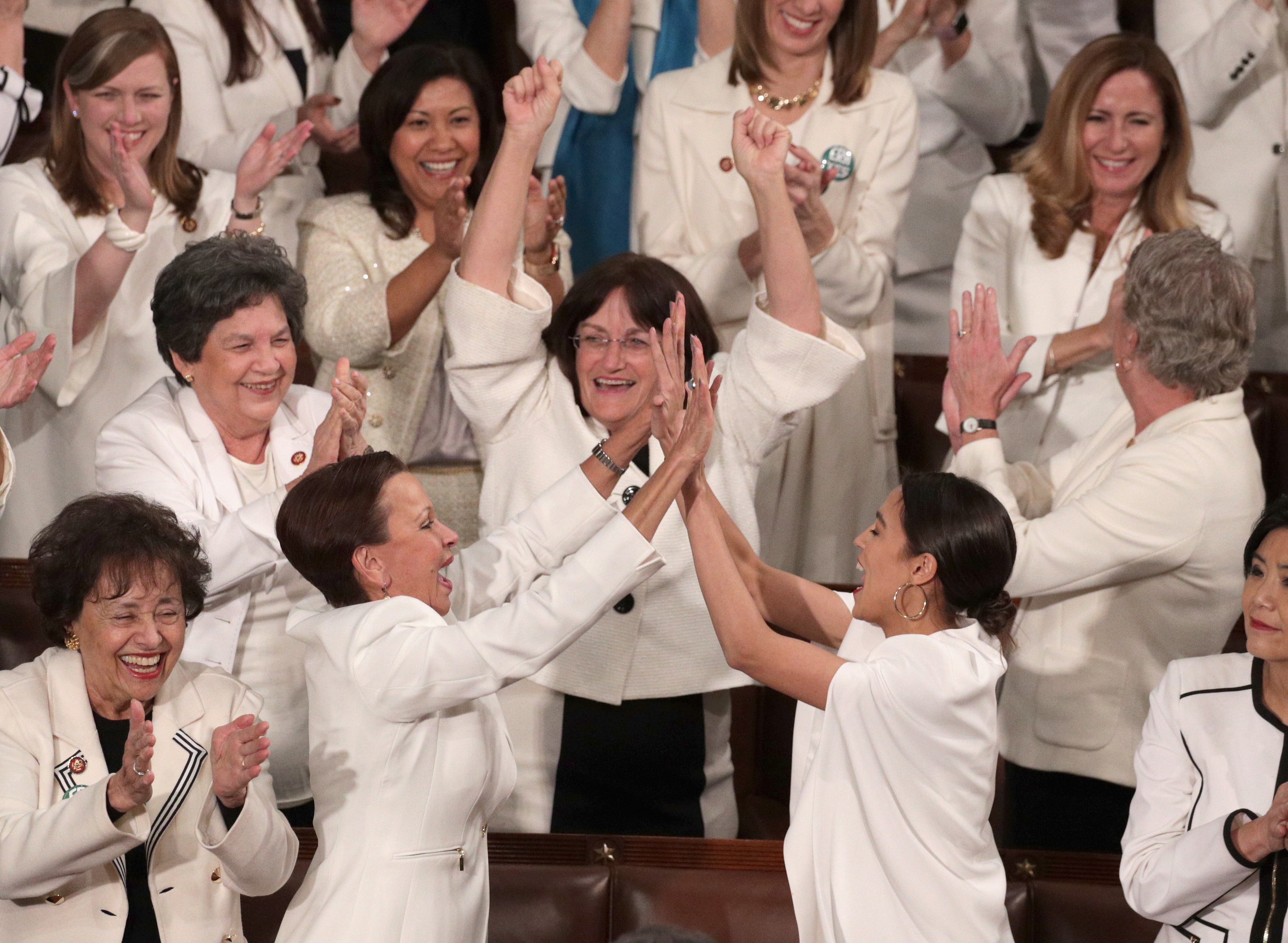 Rep. Alexandria Ocasio-Cortez (D-NY) and other female lawmakers cheer during President Donald Trump's State of the Union address in the chamber of the U.S. House of Representatives at the U.S. Capitol Building on February 5, 2019 in Washington, DC. A group of female Democratic lawmakers chose to wear white to the speech in solidarity with women and a nod to the suffragette movement. (Alex Wong—Getty Images)