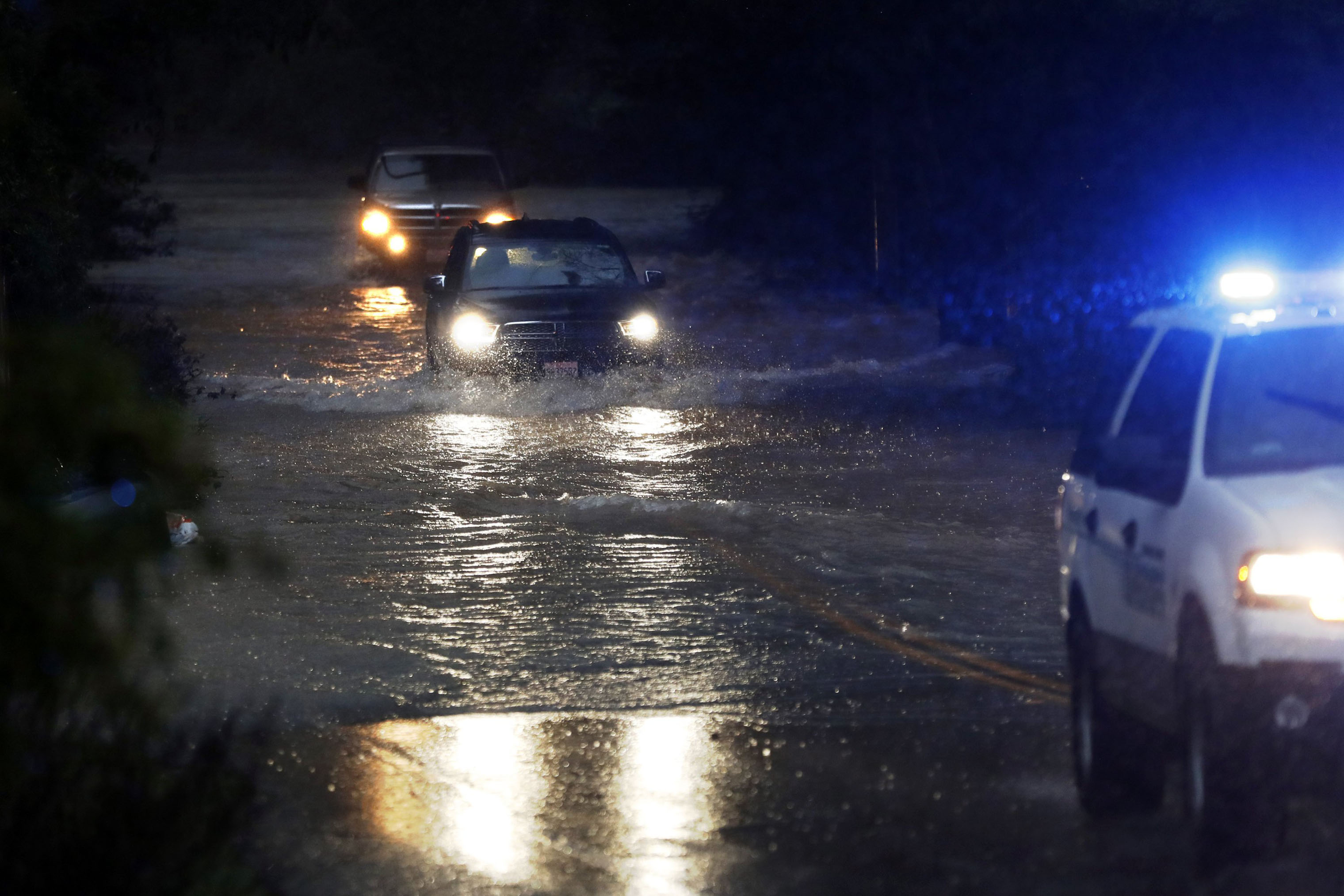 Two vehicles follow a Sonoma County Sheriff's vehicle through flooded Neeley Road as the Russian River rises towards flood stage in Guerneville, California on Feb. 26, 2019. The Sonoma County Sheriff's Office issued mandatory evacuations in communities along the Russian River and urged people to "evacuate now." As of 9:32 p.m. on Feb. 26, the river had reached 35.1 feet. (Scott Strazzante—San Francisco Chronicle/Polaris)