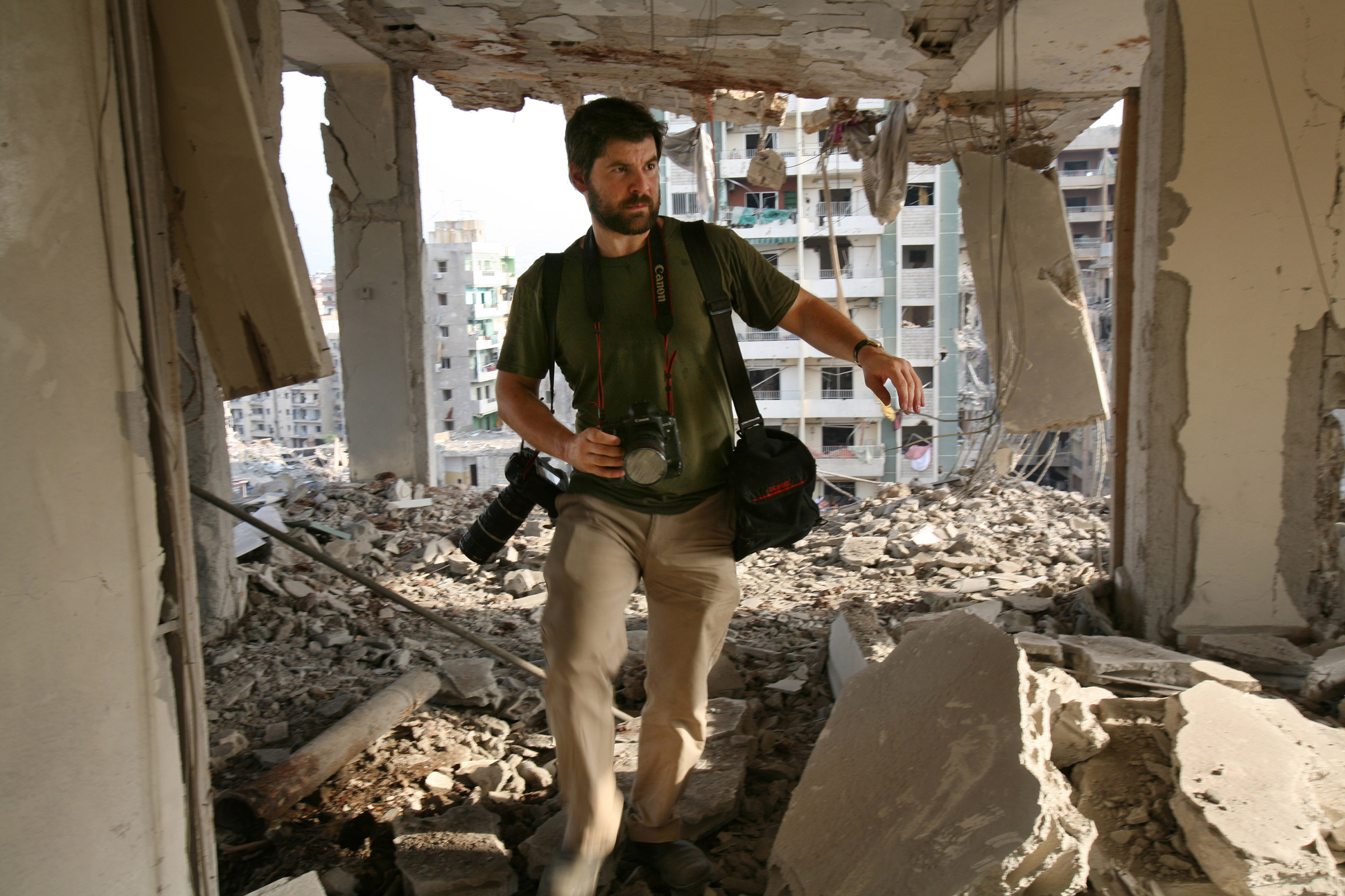 Getty Images photographer Chris Hondros walks through the ruins of a building in southern Beirut on Aug. 21, 2006. Hondros was killed while on assignment in Misrata, Libya, on April 20, 2011. (Getty Images)
