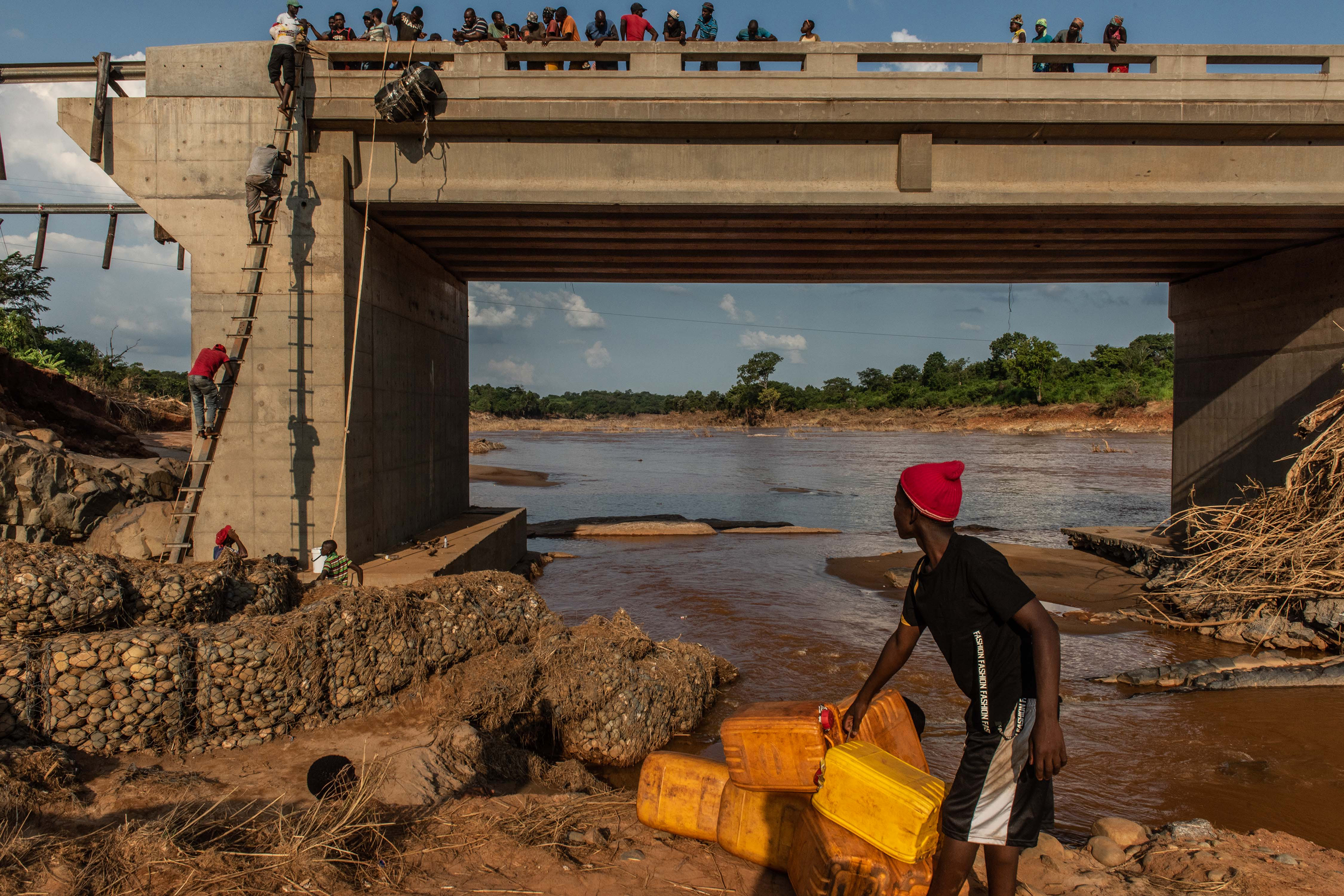 People climb to the top of a broken bridge, damaged during Cyclone Idai, across the Lucite River on March 26, 2019, outside of Magaro, Mozambique. (Andrew Renneisen—Getty Images)
