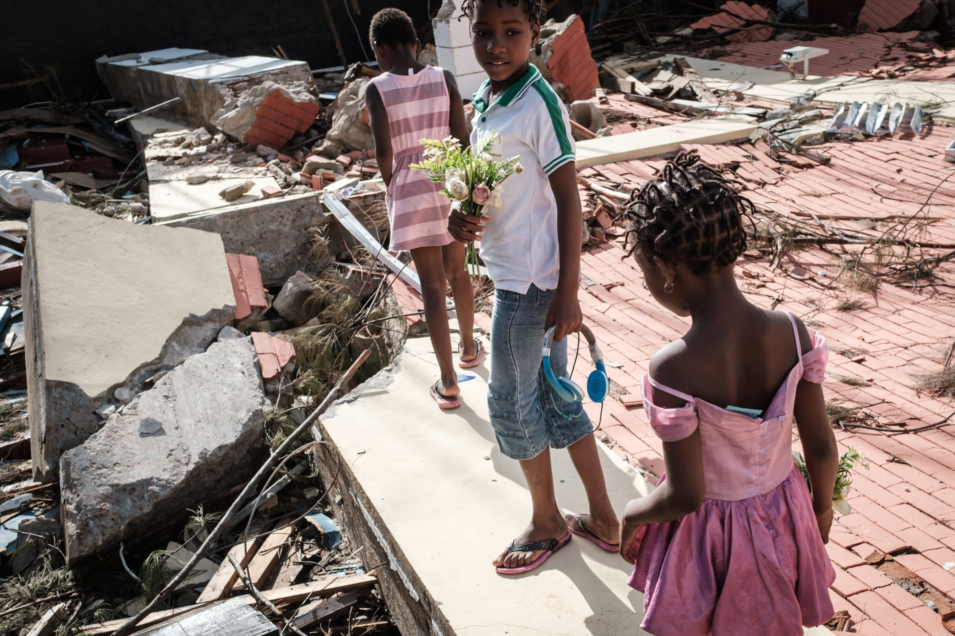 Girls collect artificial flowers from the rubble of a building destroyed by cyclone Idai at Sacred Heart Catholic Church in Beira, Mozambique, on March 24, 2019. (Yasuyoshi Chiba—AFP/Getty Images)
