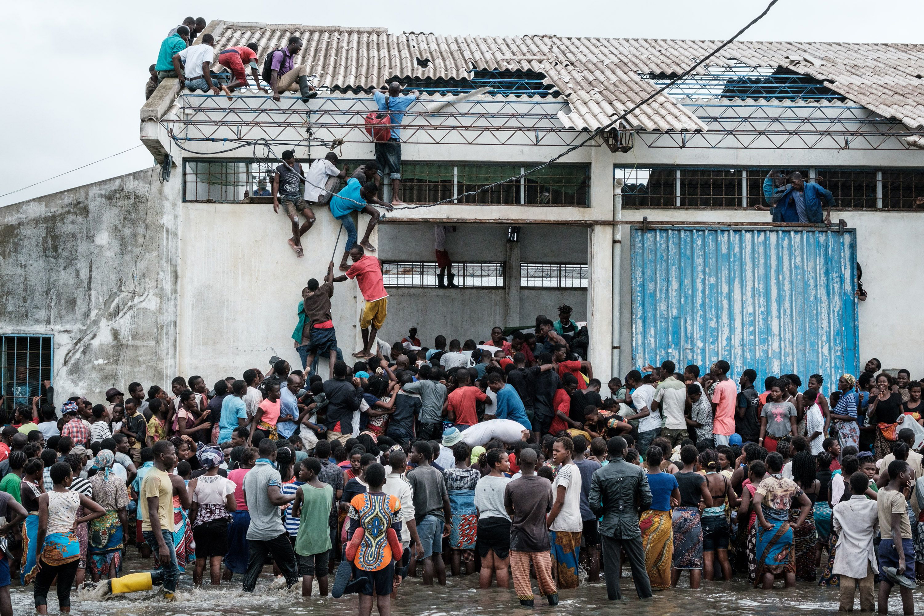People looting sacks of Chinese rice from a warehouse surrounded by water in Beira, Mozambique, on March 20, 2019. (Yasuyoshi Chiba—AFP/Getty Images)