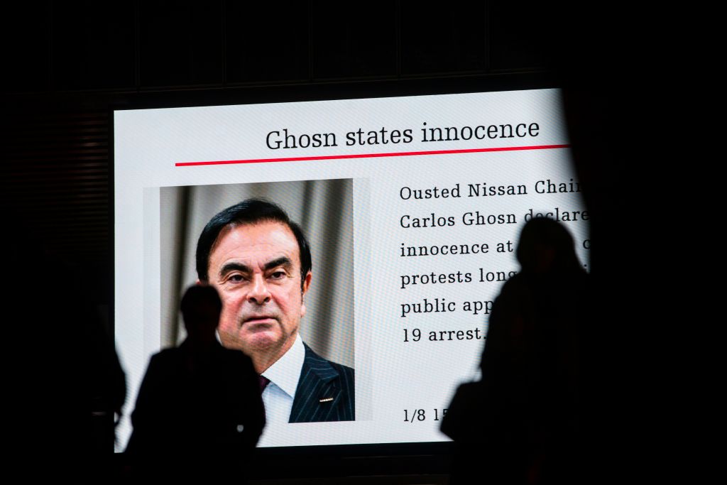 Pedestrians pass by a television screen showing a news program featuring former Nissan chief Carlos Ghosn in Tokyo on Jan. 8, 2019. (Behrouz Mehri—AFP/Getty Images)