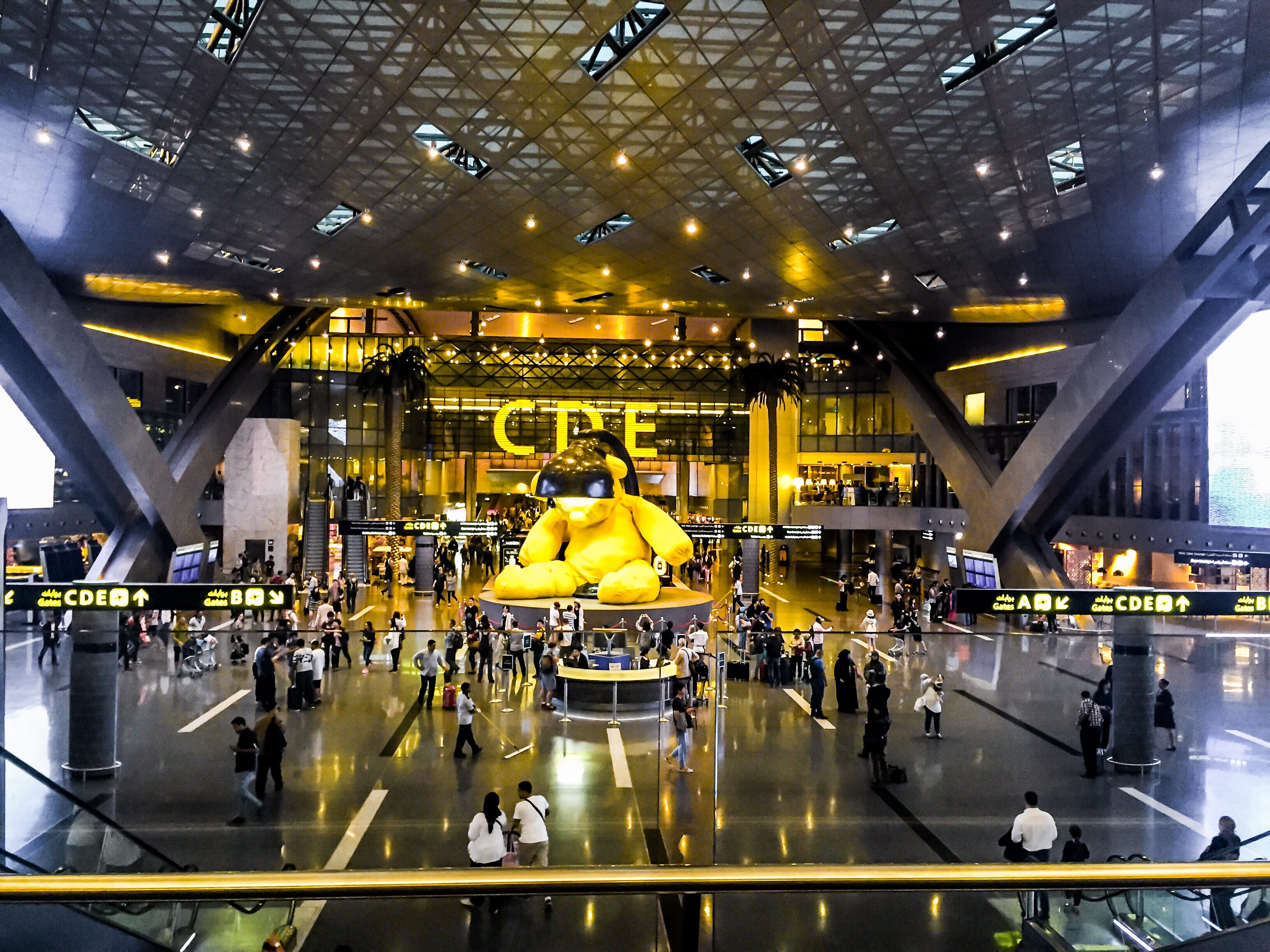 Main area of Hamad International Airport, with a giant yellow teddy bear statue in the center. (Mila J—Getty Images)