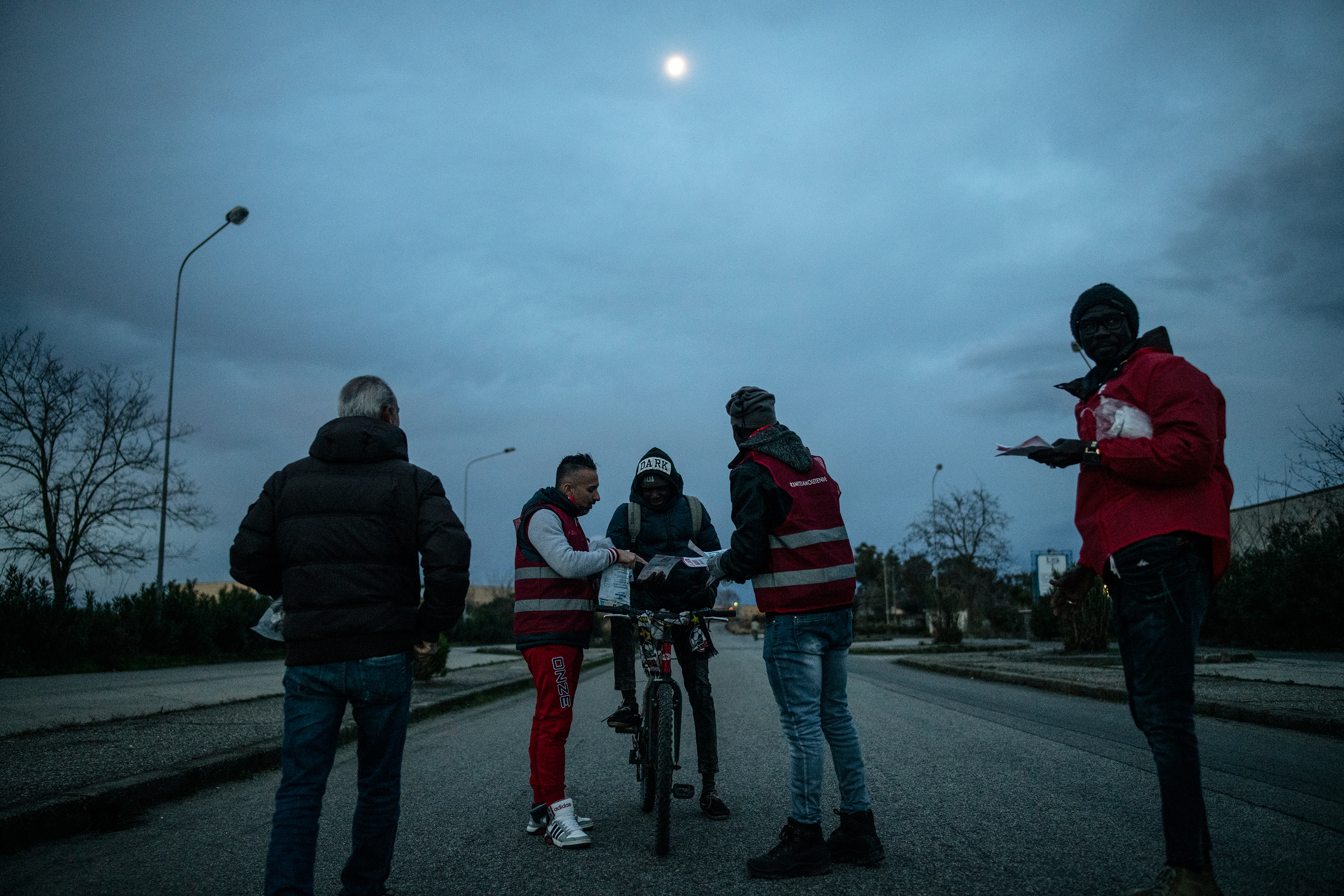 Migrant workers receive educational pamphlets about their rights in Italy, Jan. 24, 2019. (Lynsey Addario for TIME)