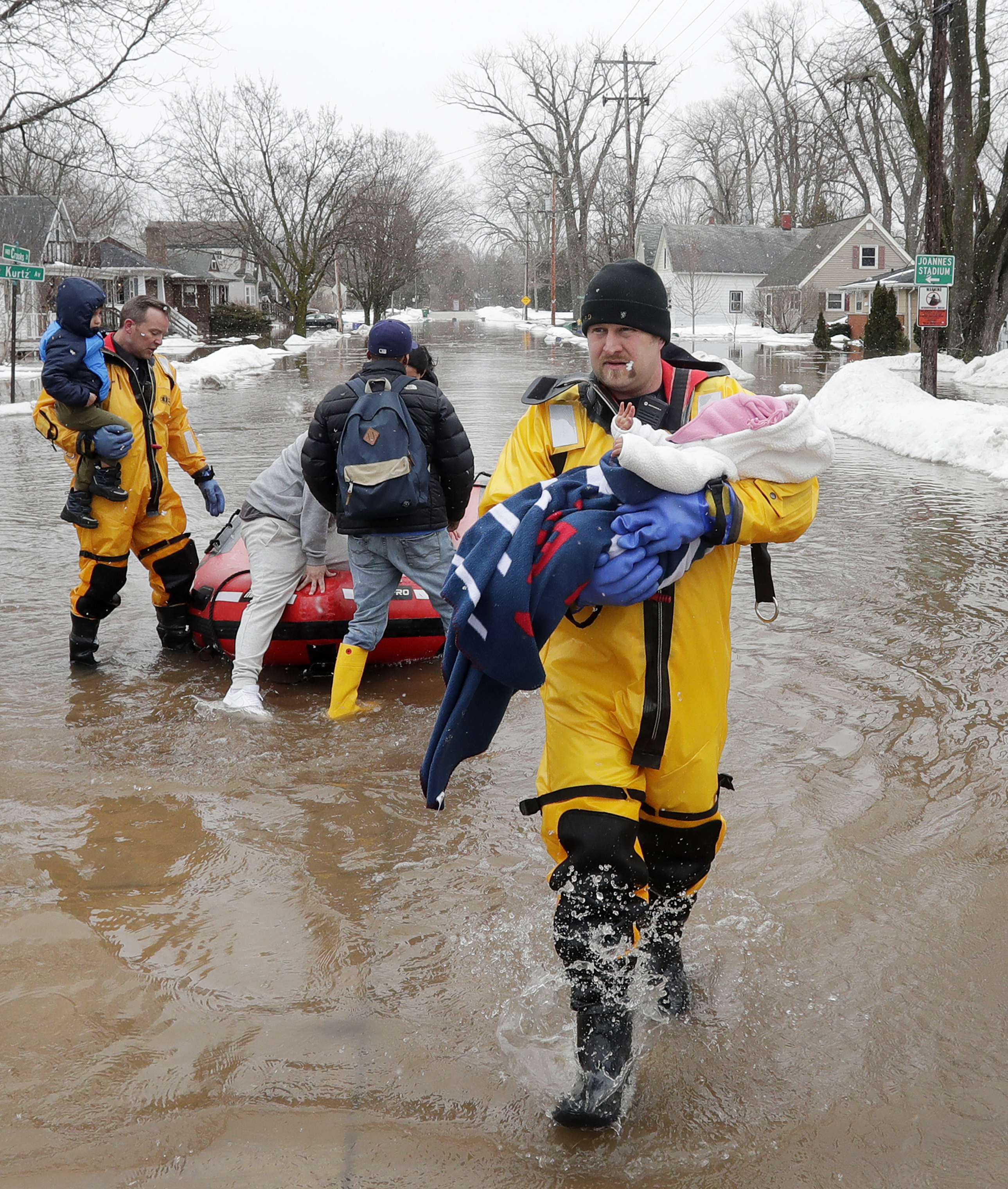 Firefighter Brian Farr carries a baby from the boat as the GBFD assisted residents with home evacuations on Crooks Street due to the East river flooding on March 15, 2019 in Green Bay, Wisconsin. (Adam Wesley—The Post-Crescent via AP)