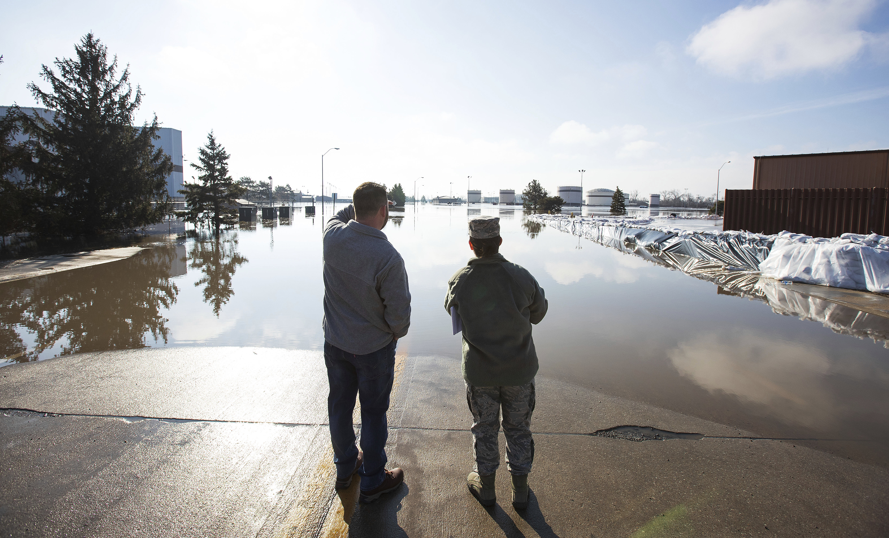 Luke Thomas and Air Force Tech Sgt. Vanessa Vidaurre look at a flooded portion of Offutt Air Force Base on March 17, 2019, in Bellevue, Nebraska. (Z Long—Omaha World-Herald via AP)
