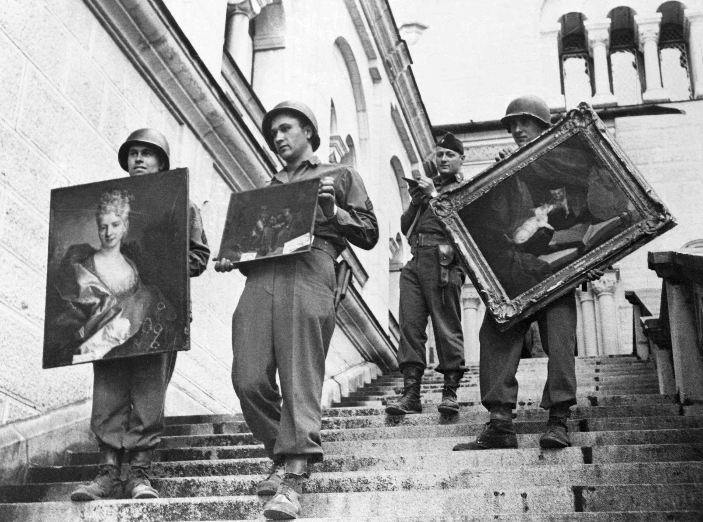 While a lieutenant checks his list (background), 7th Army soldiers carry three valuable paintings down the steps of Neunschwanstein Castle at Fussen, Germany, where they were a part of the collection looted by the Nazis from conquered countries. (Bettmann/Getty Images)