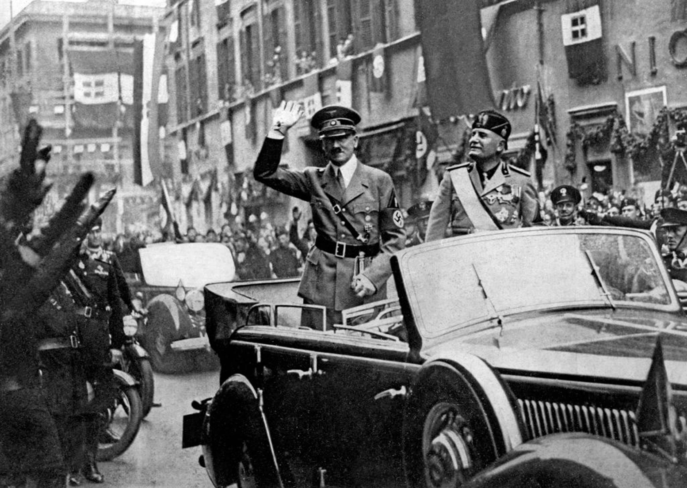 Adolf Hitler (left) and Benito Mussolini in a car, saluting the crowd that gathered along the thoroughfare Corso Vittorio Emanuele in Rome, in May 1938. (Mondadori Portfolio—Getty Images)