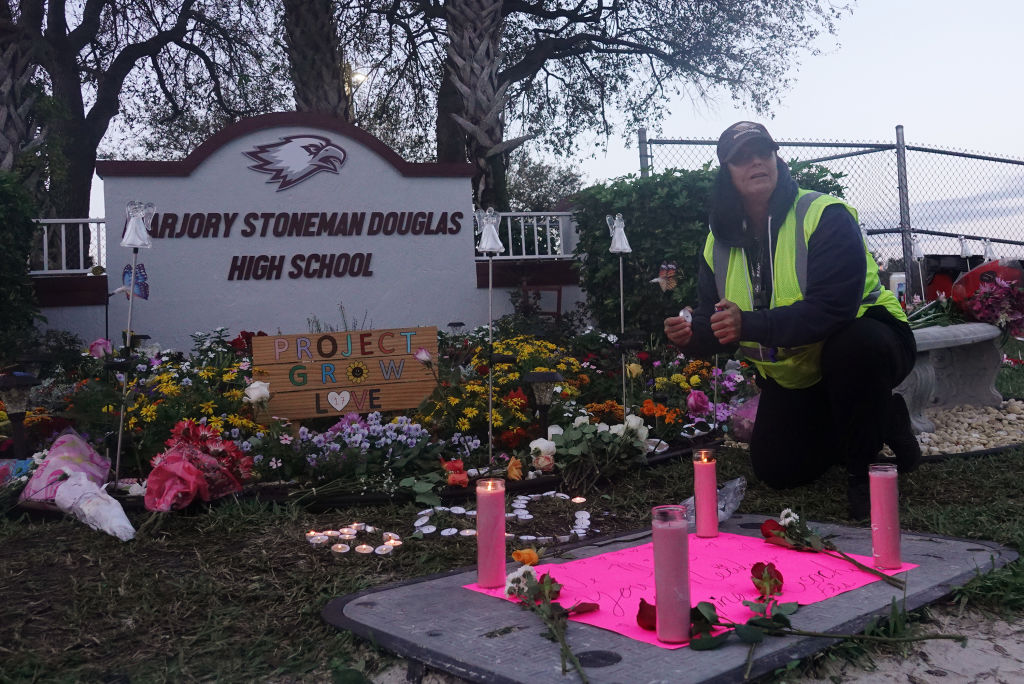 School crossing guard Wenday Behrend of Parkland lights a candle at the memorial garden outside of Marjory Stoneman Douglas High School Thursday, Feb. 14, 2019 in Parkland, Fla., on the one year anniversary of the shooting at the school. (Joe Cavaretta—Sun Sentinel/TNS/Getty Images)