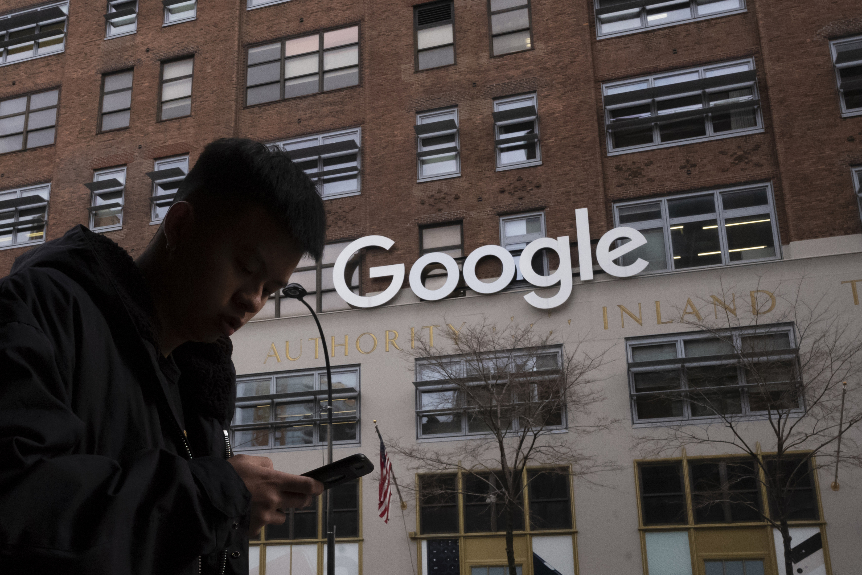 A man using a mobile phone walks past Google offices in New York on Dec. 17, 2018. A Congressional committee hearing began criticizing the spread of hate crimes in the U.S. and social media's role in the spread. (Mark Lennihan—AP)