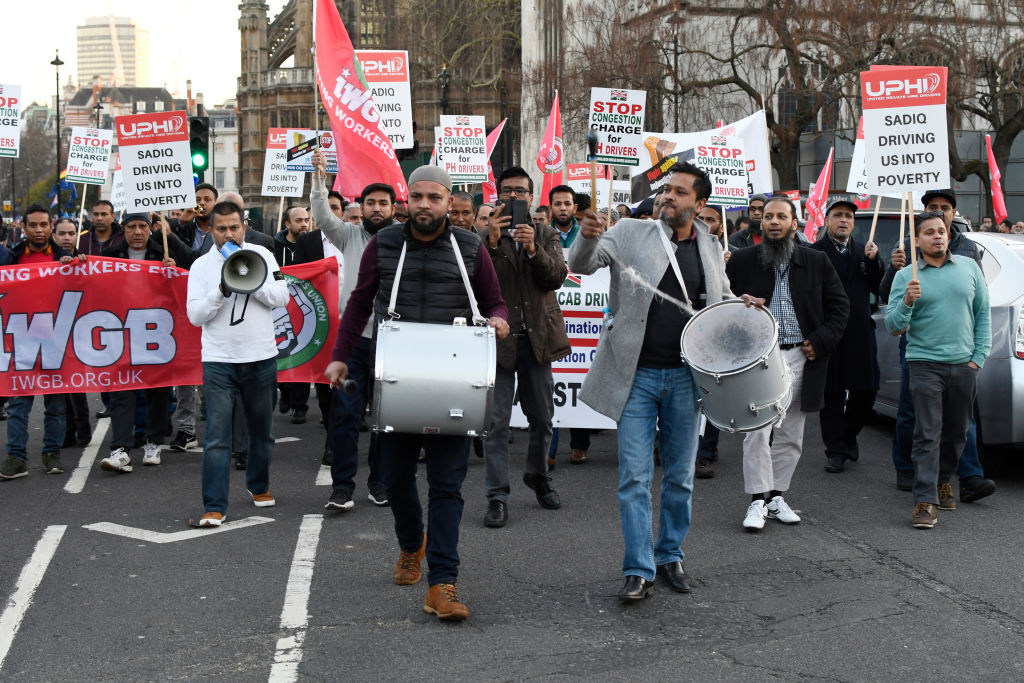 Minicab drivers seen playing drums during the protest.