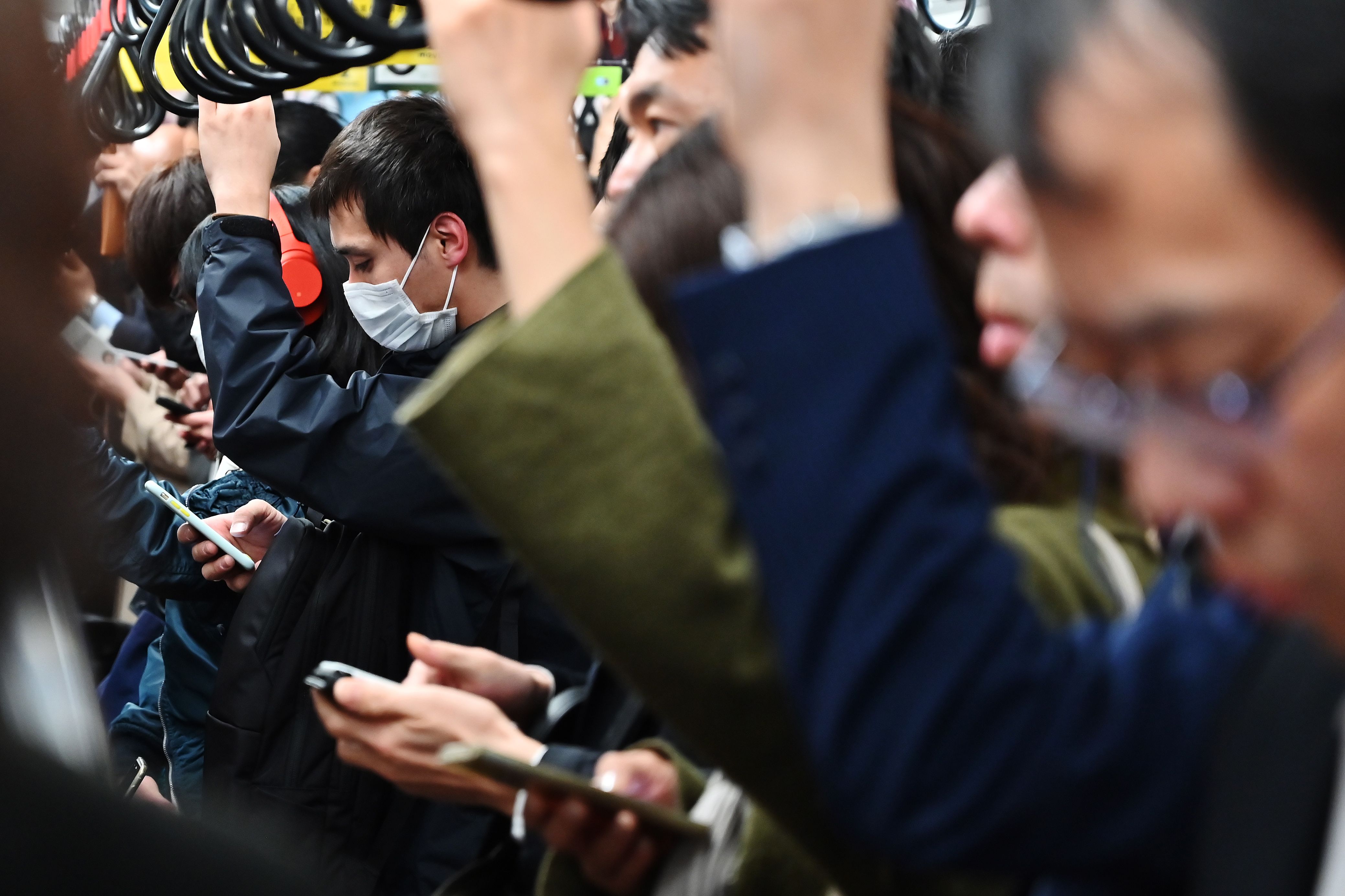 Commuters use their mobile phones while travelling on a coach of the Tokyo Metro network in Tokyo on March 26, 2019. (CHARLY TRIBALLEAU—AFP/Getty Images)