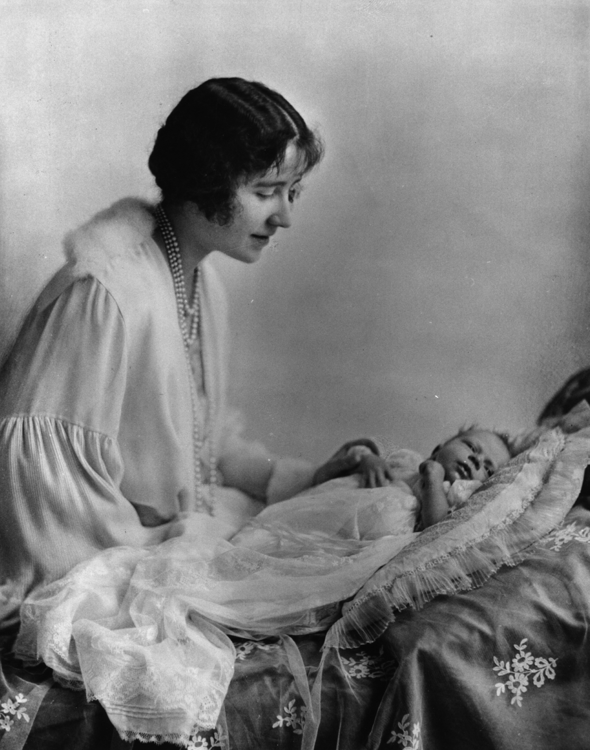 May 1926: Elizabeth, Duchess of York (1900 - 2002), looking at her first child, future Queen, Princess Elizabeth. (Speaight/Getty Images)