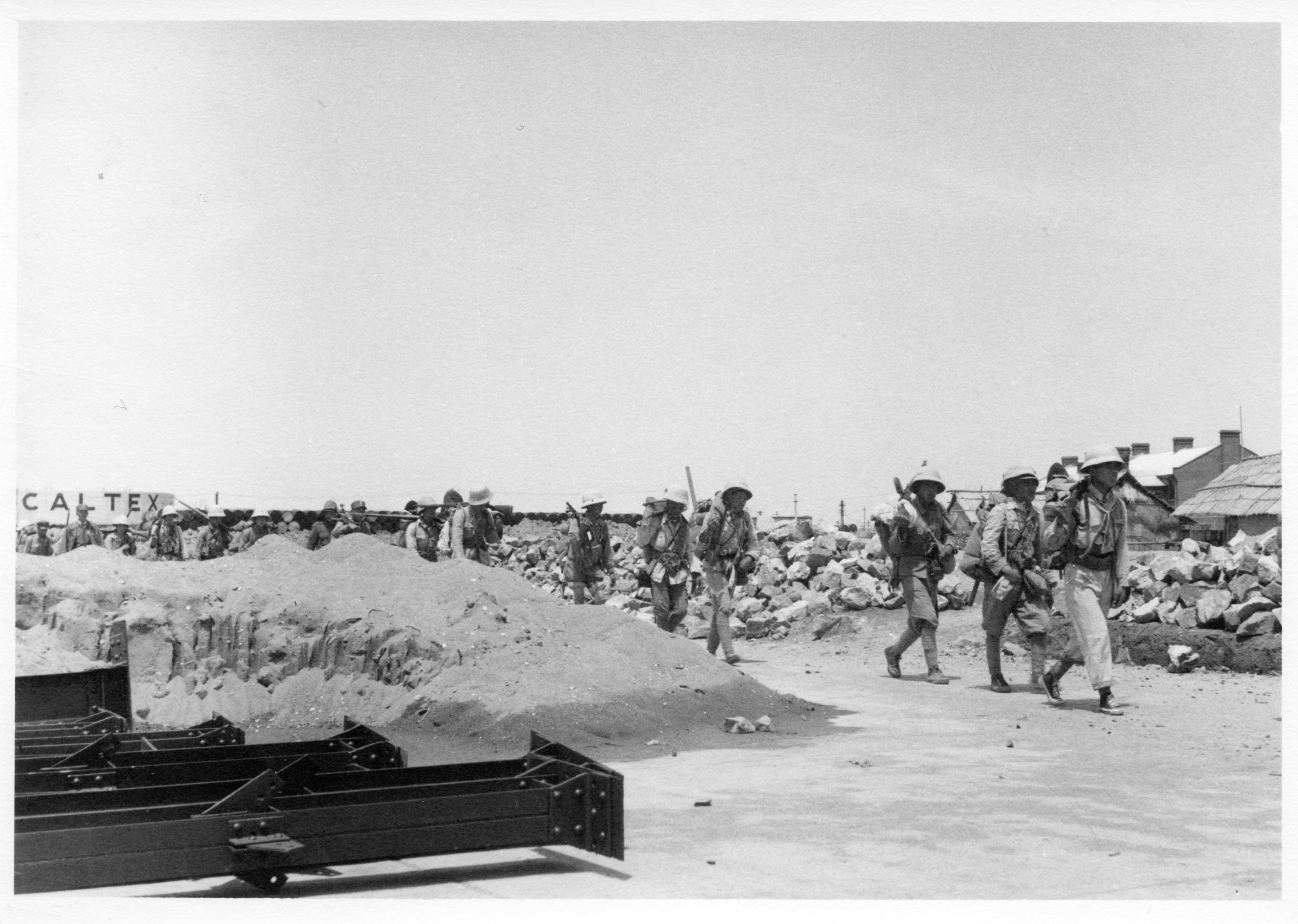 Nationalist troops march through the Caltex property to the battlefront. A Caltex oil tank is visible in the background. (Carolyn Davidson Hill)