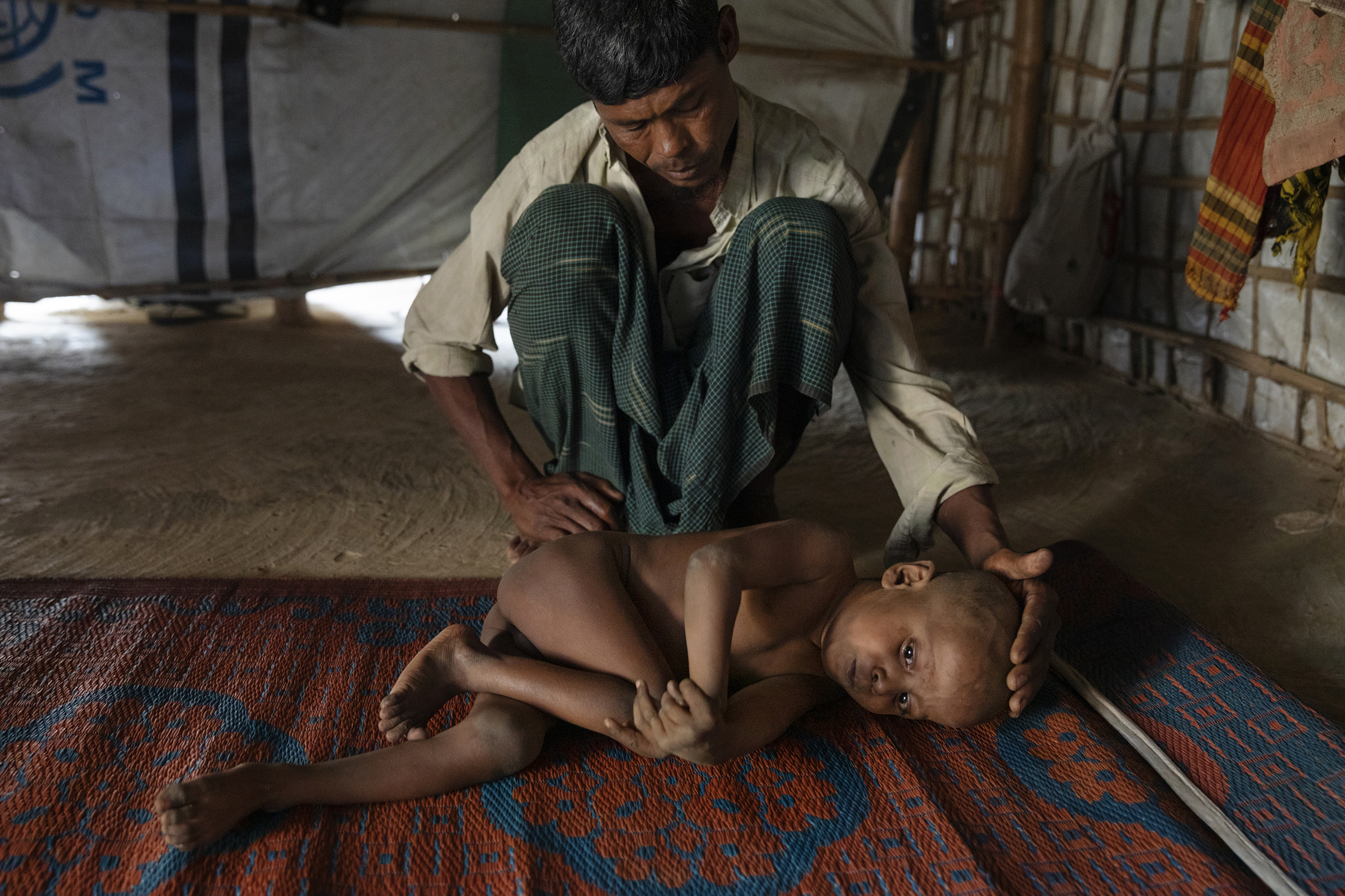 Mohammed Amin cares for his sick son, 7-year-old Mujibur Rahman, in a hut. The boy suffers from a nervous system disorder, his father said. (James Nachtwey for TIME)