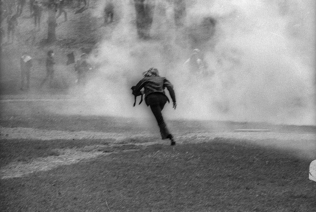 An unidentified demonstrator runs through a cloud of teargas on the Kent State University Commons during a student antiwar protest, Kent, Ohio, May 4, 1970. The protests, initially over the US invasion of Cambodia, resulted in the deaths of four students (and the injuries of nine others) after the National Guard opened fire on students. (Howard Ruffner—Getty Images)