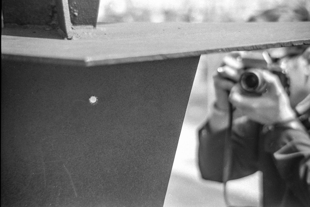 Closeup of a bullet hole left in a metal sculpture after the Ohio National Guard opened fire on antiwar protesters at Kent State University, Kent, Ohio, May 4, 1970. In the background, an unidentified person photographs the hole from the opposite side. The sculpture, 'Solar Totem #1' by Don Drumm, is located outside Taylor Hall. (John Filo—Getty Images)