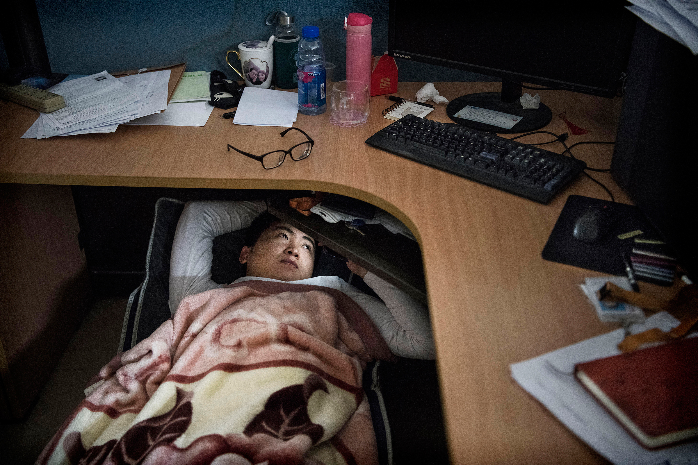 A Huawei employee watches a program on his smartphone as he rests at his cubicle during a lunch break at the research and development area in the Bantian campus in Shenzhen, China, on April 12, 2019.