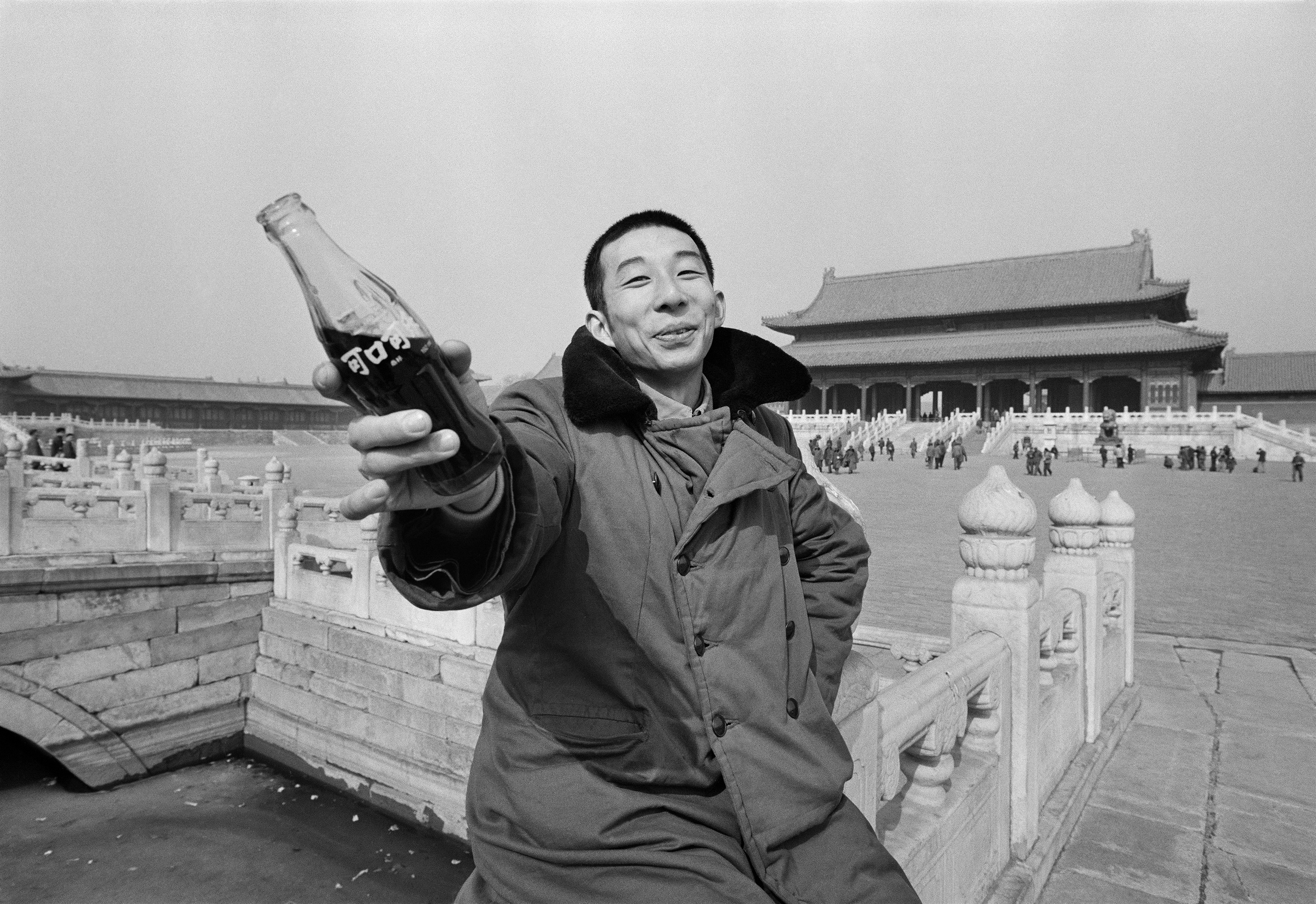 A young man holds a glass bottle of Coca-Cola, which had just resumed production in China, outside the Forbidden City, Beijing, 1981. (Liu Heung Shing)