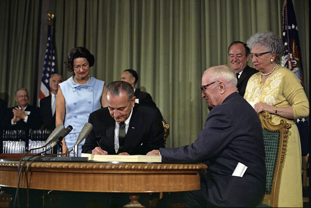 President Lyndon Johnson signing the Medicare bill, in Independence, Missouri, as Harry Truman looks on, July 30, 1965. (Universal History Archive—UIG via Getty Images)