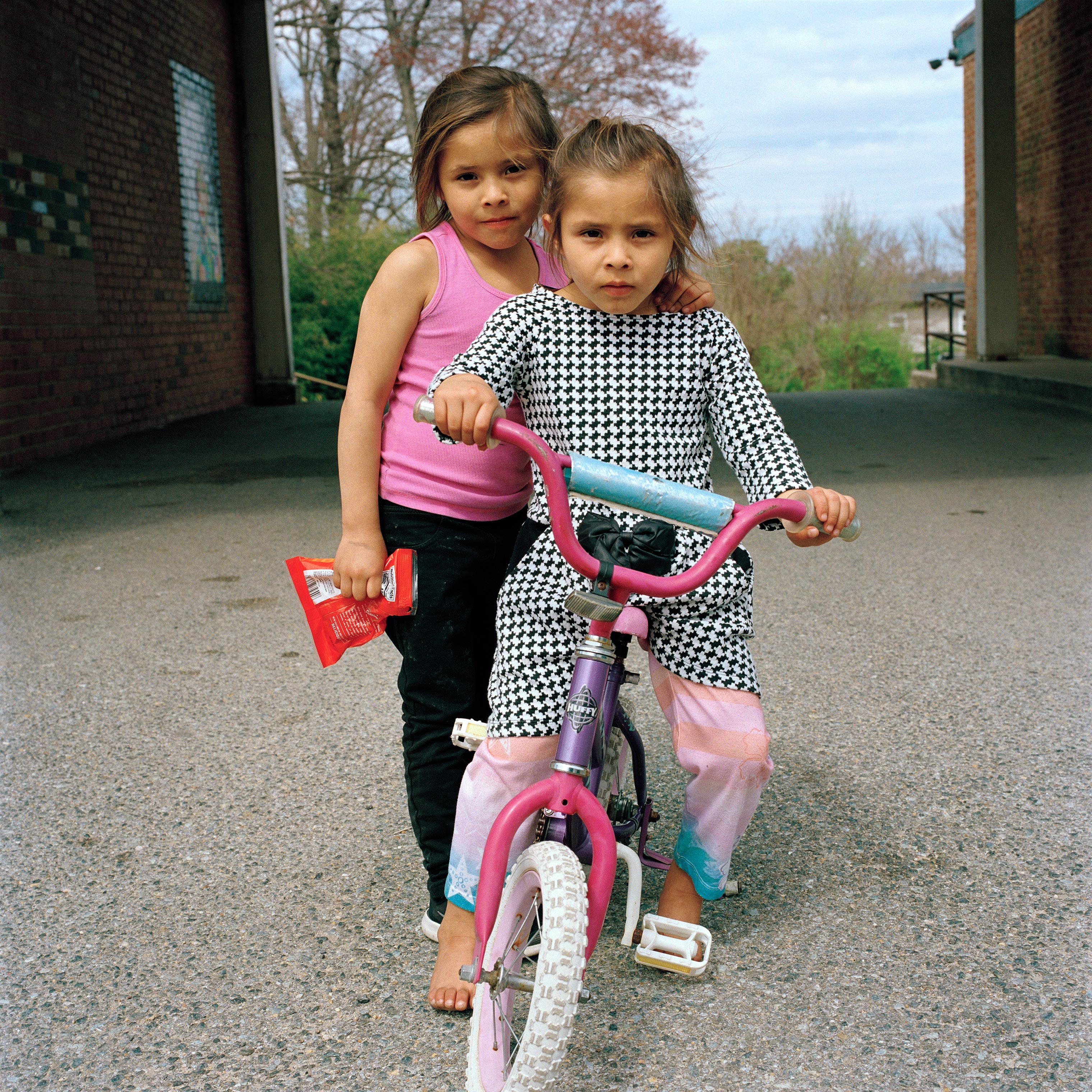 Sayra, left, and Cheyli play with a new bicycle on April 4. (Federica Valabrega)
