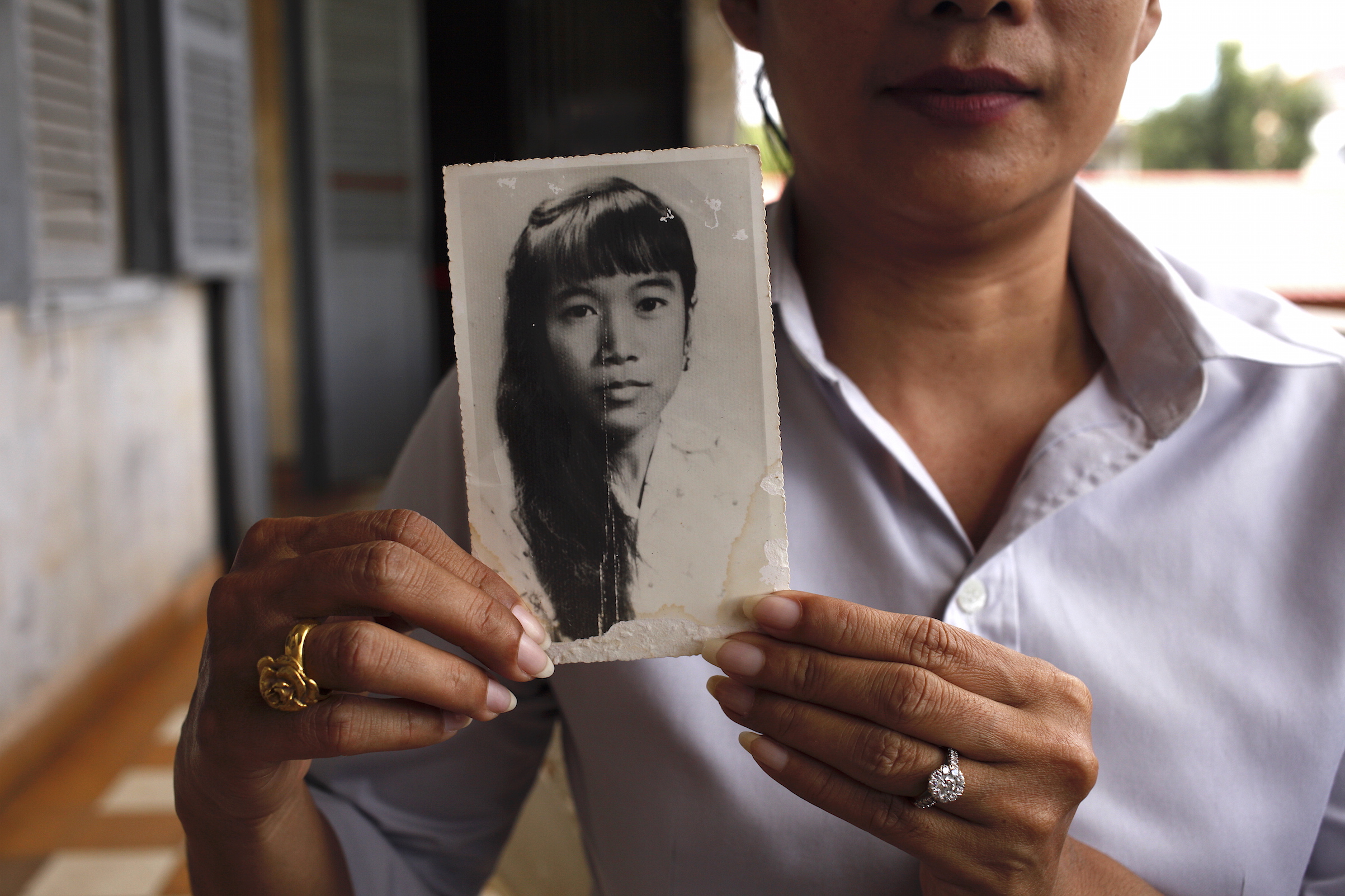 Chheng Samin was born under a pagoda shortly after the fall of Phnom Penh. She holds a picture of her mother, Chheng Samit, who survived the Khmer Rouge but died young. She now works at Tuol Sleng. (Photographer: Andy Kopsa)
