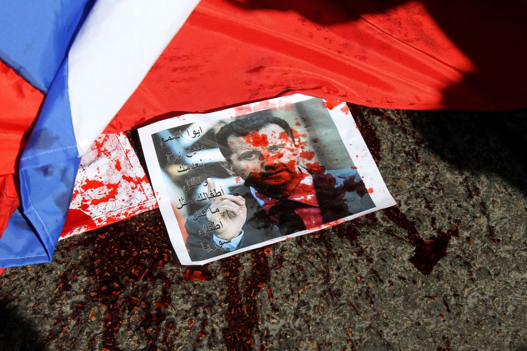 A picture of Syria's embattled President Bashar Assad sprayed with red paint lies on the ground next to a Russian flag about to be set on fire by protesters opposed to the Syrian regime during a demonstration outside the Russian embassy in Beirut on February 5, 2012. (Anwar Amro—AFP/Getty Images)
