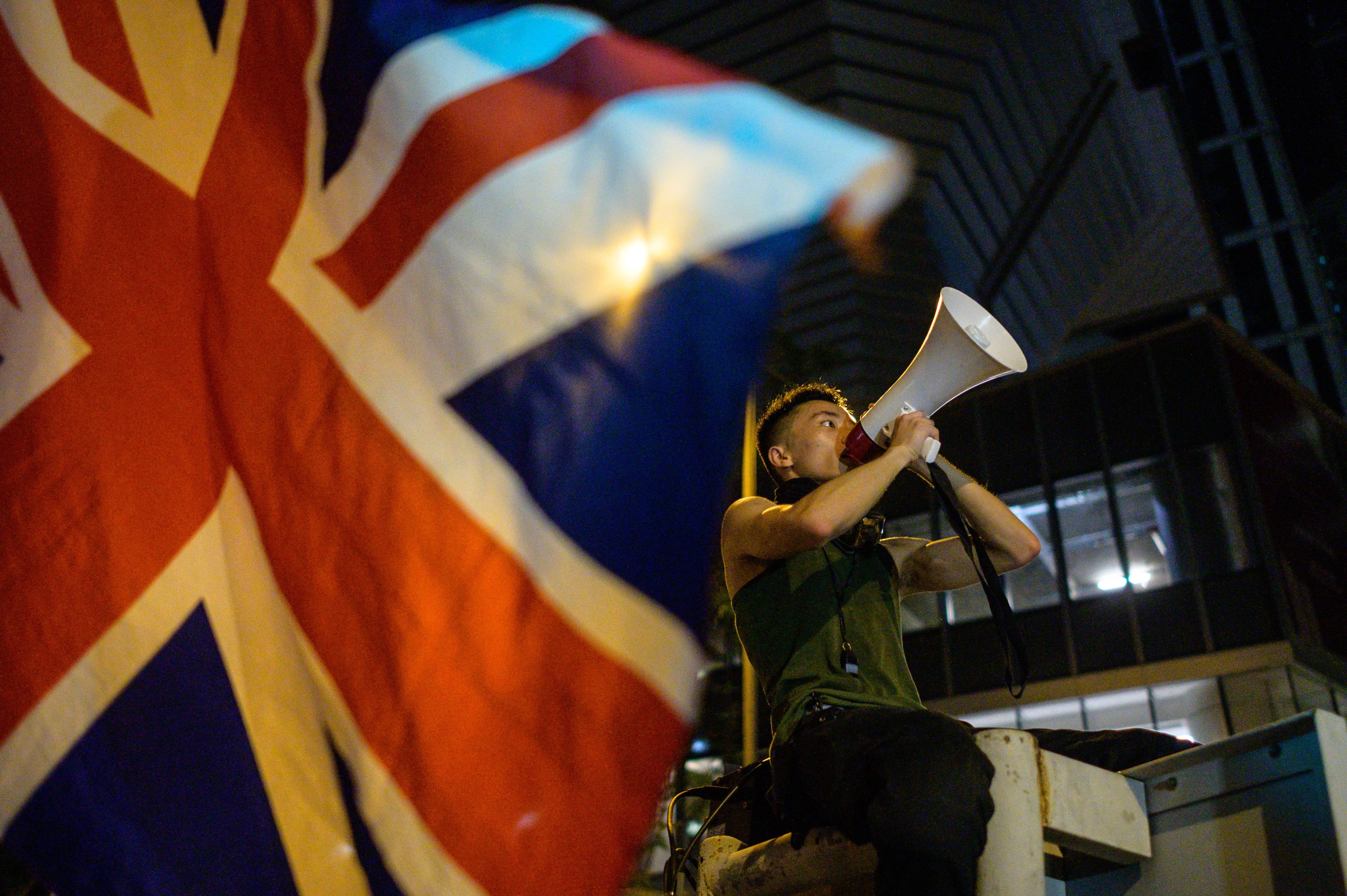 A British Union Jack flag is waved from the ground as a protester uses a loud hailer to speak outside the police headquarters in Hong Kong, early on June 27, 2019. (ANTHONY WALLACE—AFP/Getty Images)