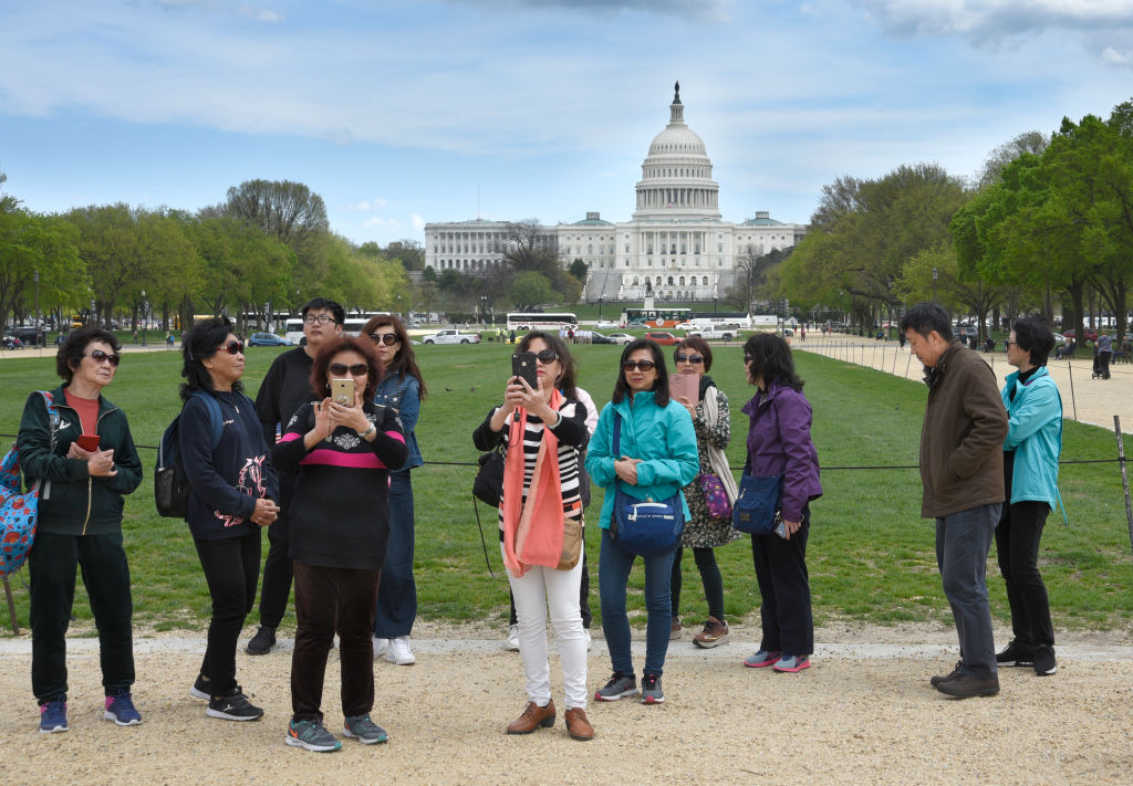 A group of Chinese tourists take photographs on the National Mall with the U.S. Capitol in the background. (Robert Alexander – Getty Imagaes)