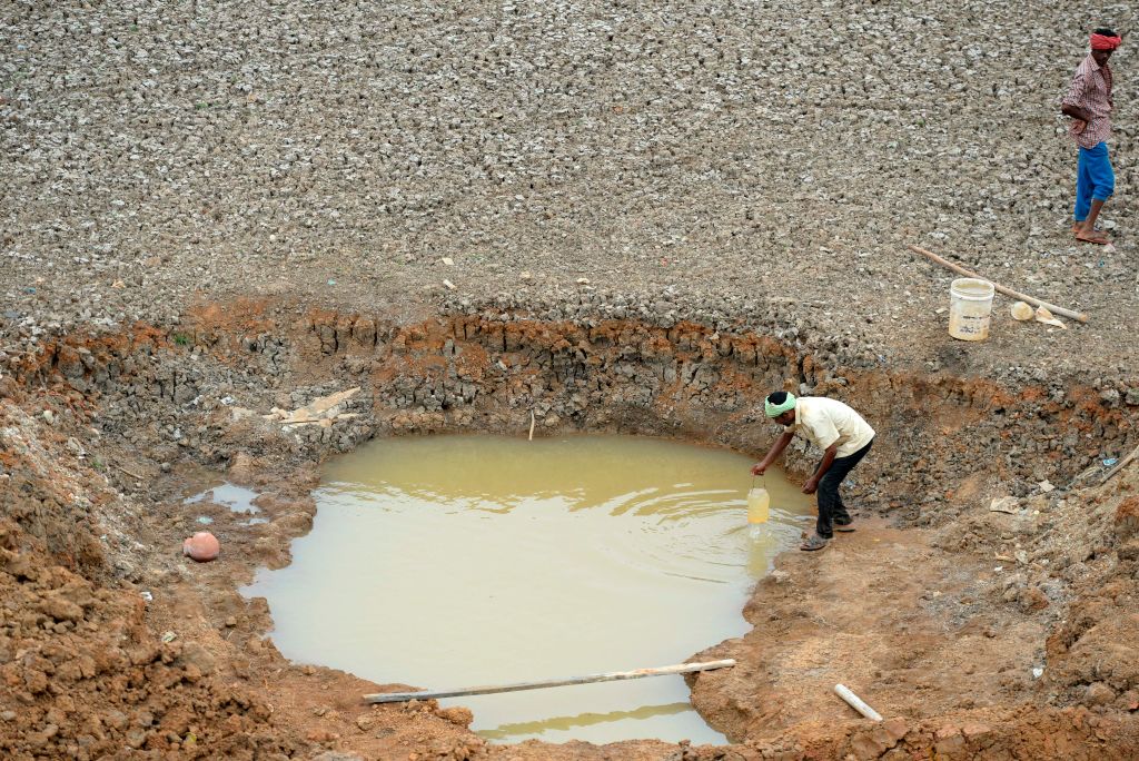 Indian workers collect water from the Puzhal reservoir on the outskirts of Chennai on June 20, 2019. - Water levels in the four main reservoirs in Chennai have fallen to one of its lowest levels in 70 years, according to local media reports. (ARUN SANKAR—AFP/Getty Images)