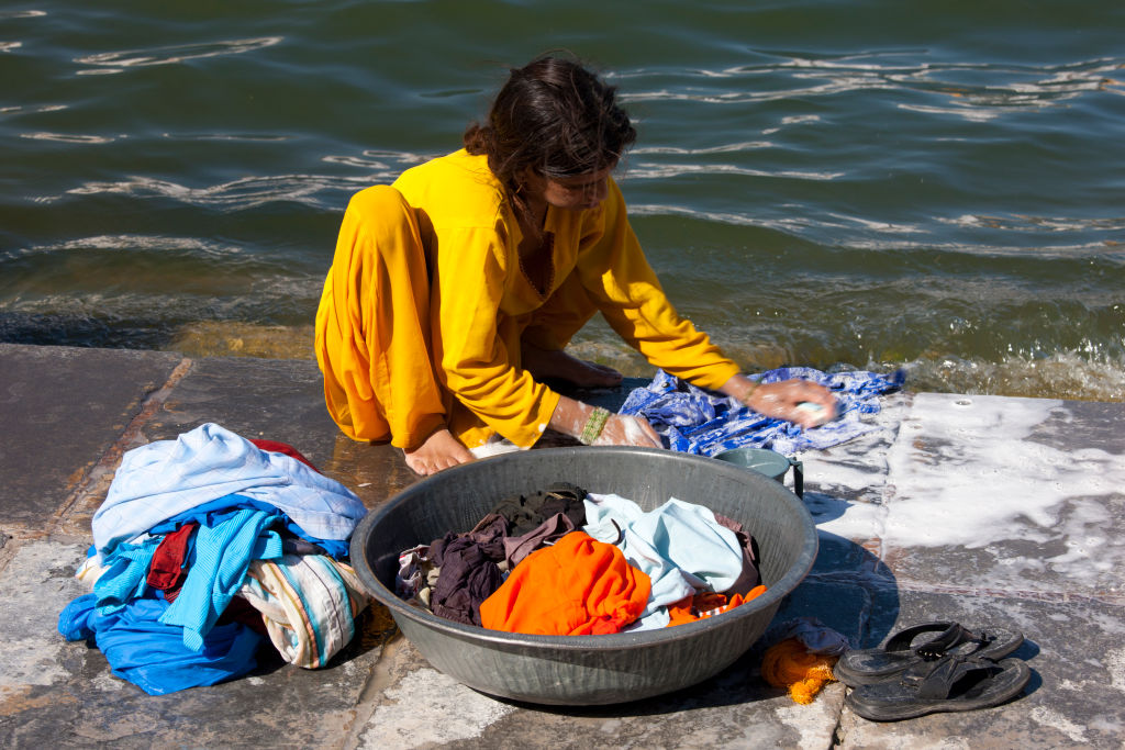 Young Indian girl squatting down to do her laundry in the waters of Lake Pichola, Udaipur, Rajasthan, Western India (Tim Graham—Getty Images)