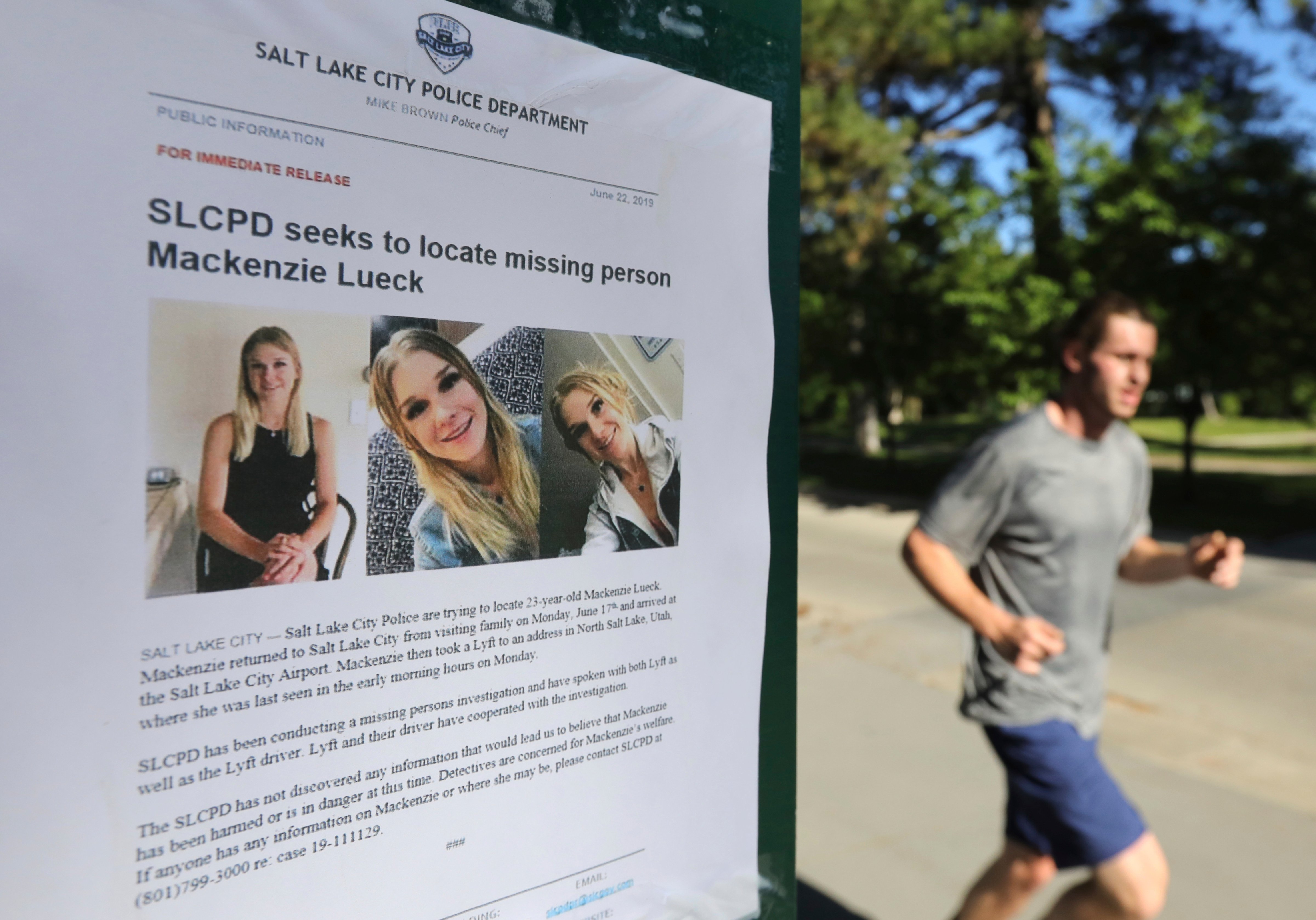 In this June 24, 2019 file photo, a jogger runs pass a poster of Mackenzie Lueck at Liberty Park in Salt Lake City. One person was taken into custody Friday, June 28, in connection with the disappearance of Lueck, a Utah college student who disappeared 11 days ago. (Rick Bowmer—AP)
