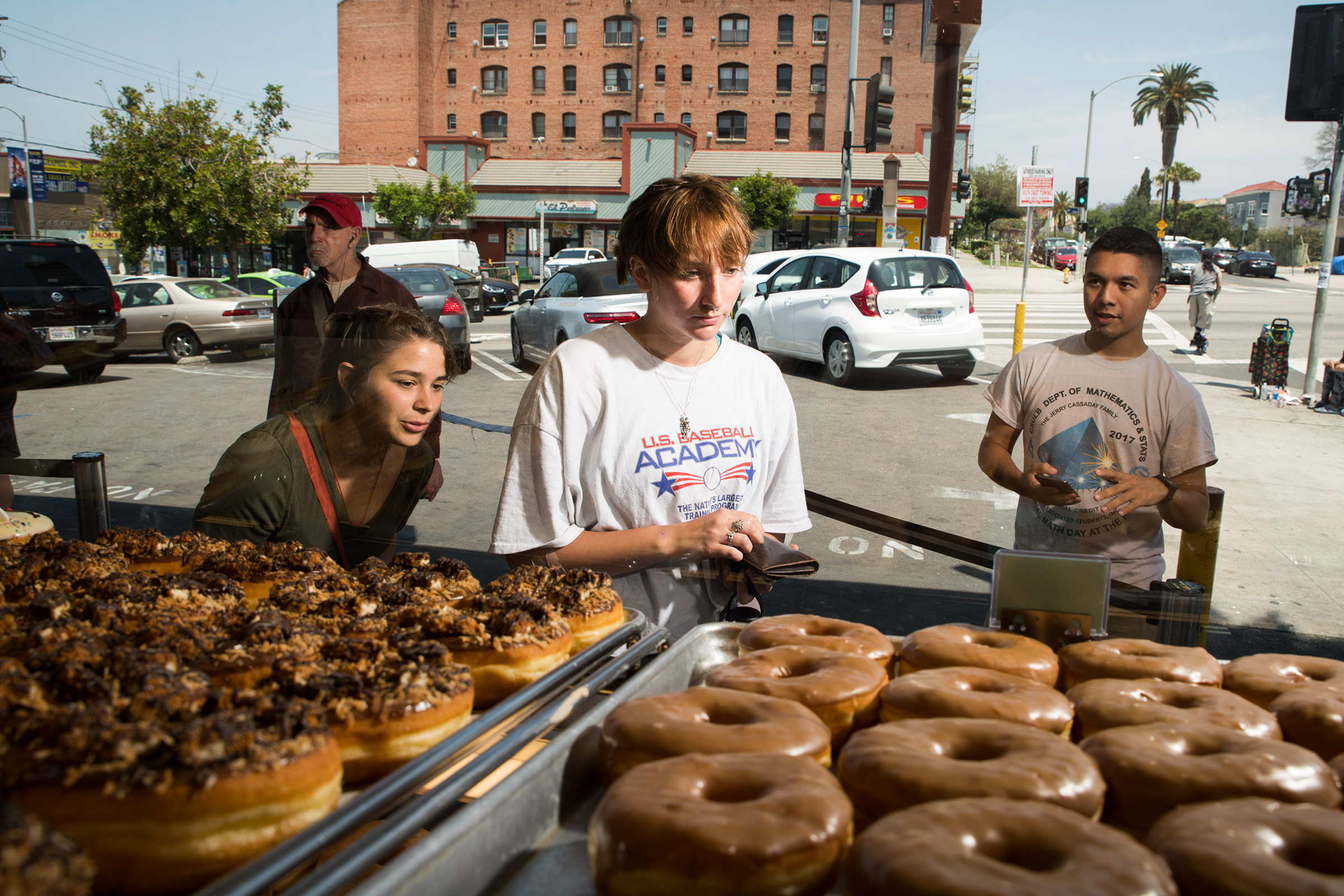 Katy McAfee, left, Abigail Logan, center, and Matthew Ortega pick out doughnuts at California Donuts in Los Angeles on June 6, 2019. (Theo Stroomer for TIME)
