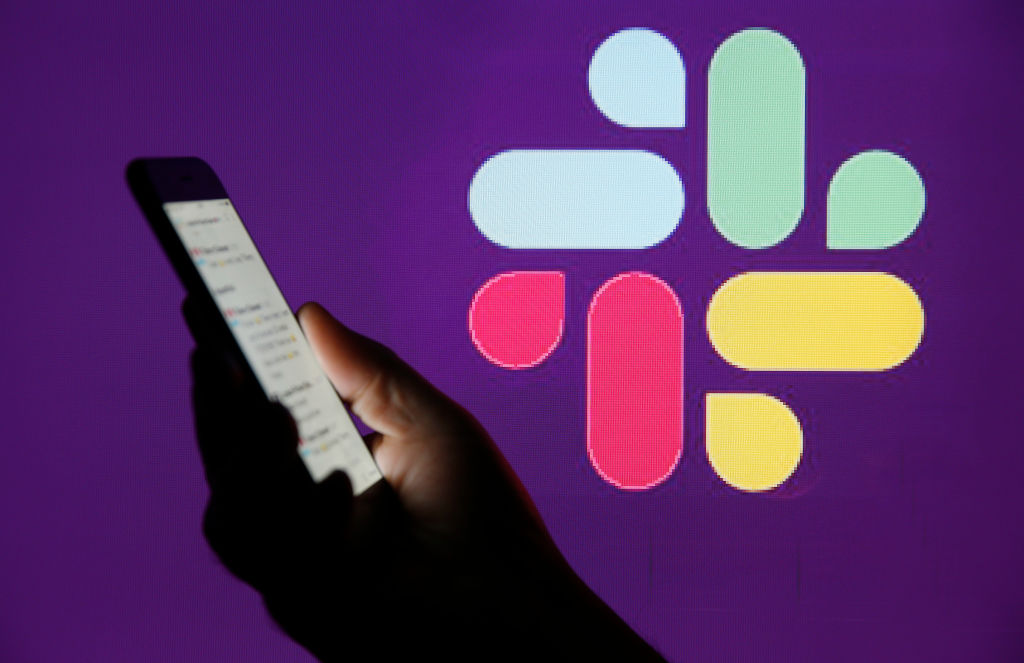 In this photo illustration, the Slack logo is displayed on the screen of an Apple iPhone in front of a computer screen displaying a Slack logo on February 6, 2019 in Paris, France. (Chesnot&mdash;Getty Images)