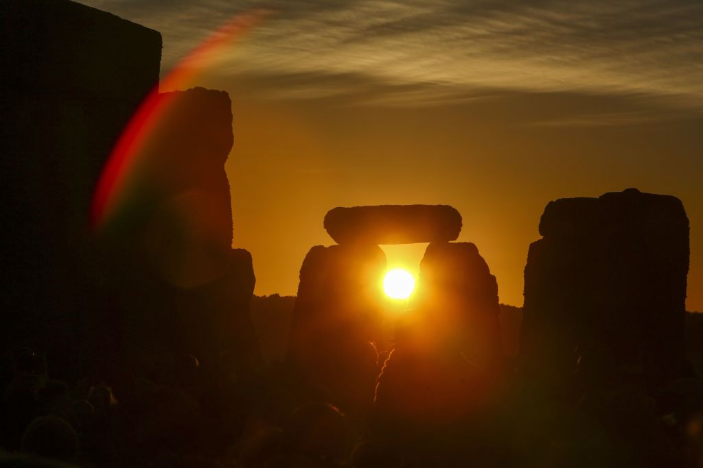Revelers watch the sunrise as they celebrate the summer solstice at Stonehenge in Wiltshire, England on June 21, 2018. (GEOFF CADDICK—AFP/Getty Images)