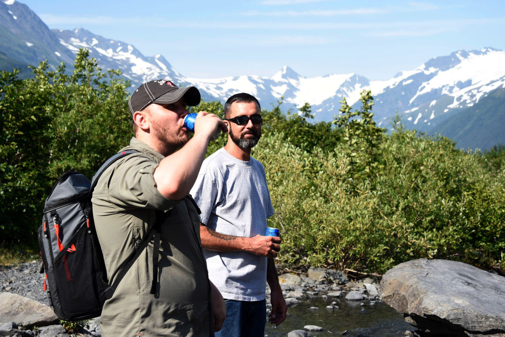 Sam Lightle, left, from Anchorage, and Brandon York from Jacksonville, Florida, take in the scenery along a creek below the Byron Glacier on July 4, 2019 near Portage Lake in Girdwood, Alaska. Alaska is bracing for record warm temperatures and dry conditions in parts of the state. (Lance King—Getty Images)