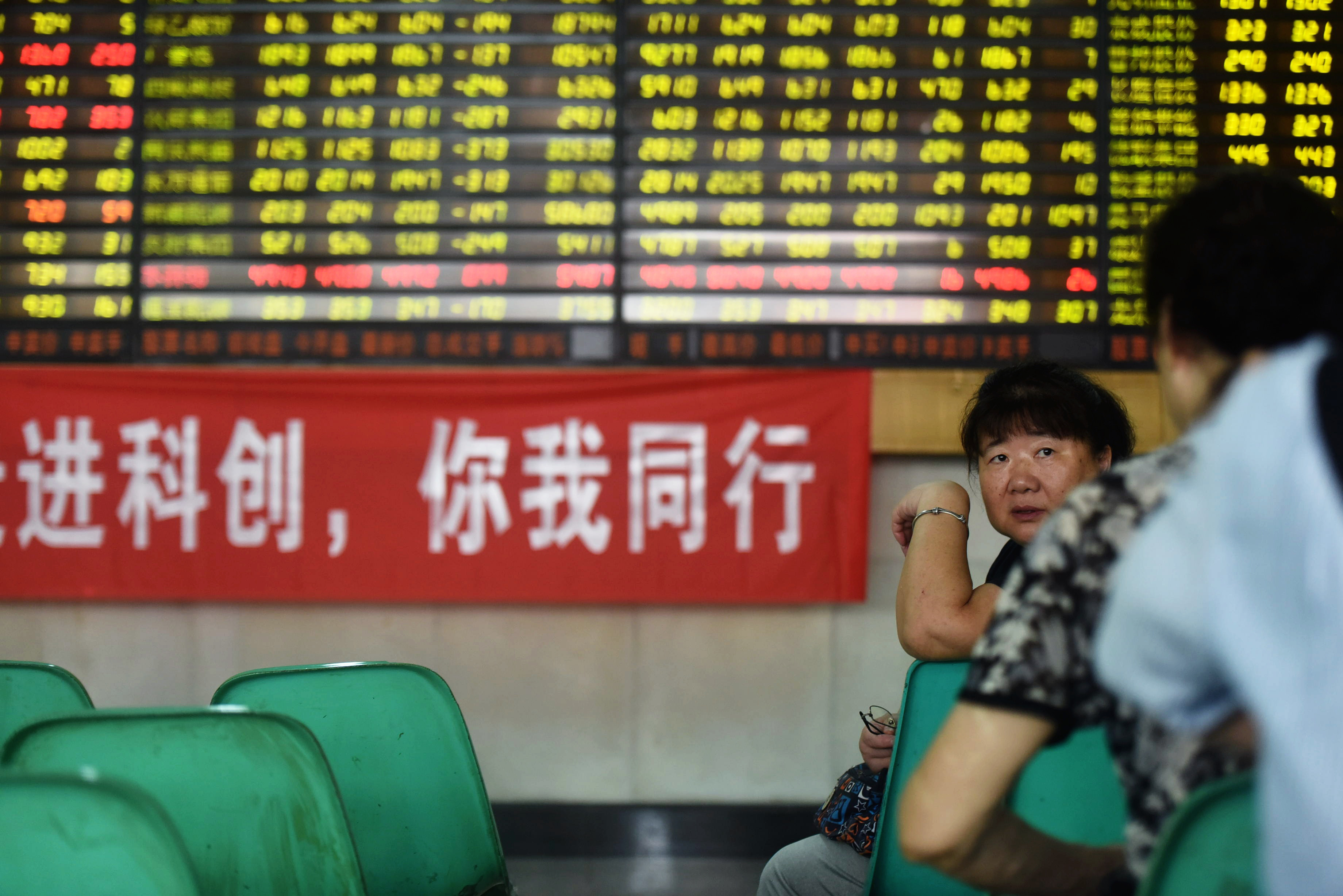 Stock investors chat beside a banner promoting the newly launched STAR market in a brokerage house in Hangzhou in east China's Zhejiang province on July 22, 2019. (Chinatopix/AP)