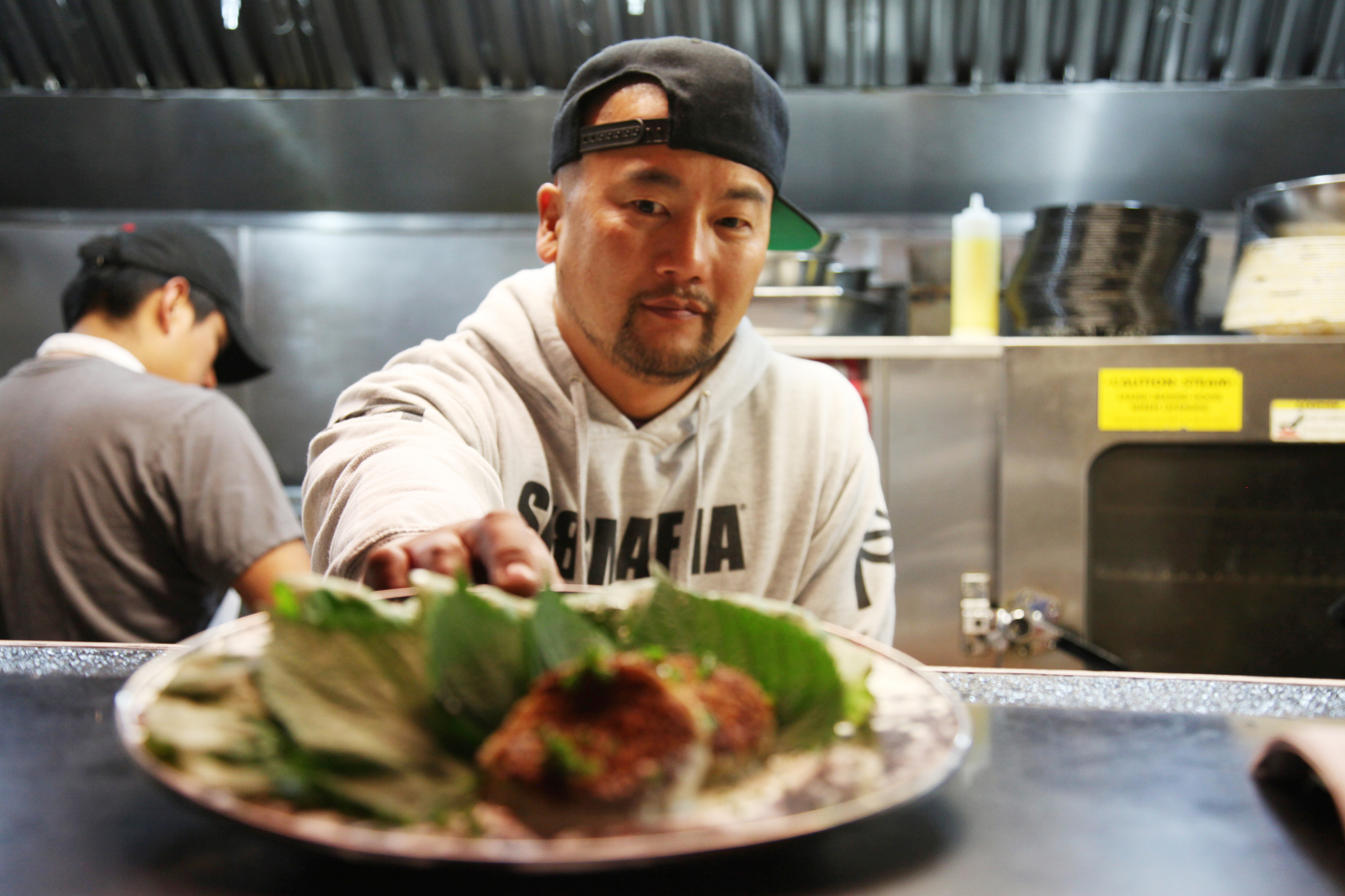 Chef Roy Choi pushes a dish through the kitchen window at his restaurant A-Frame in Los Angeles on Jan. 10, 2012. (Amy Dickerson—The New York Times/Redux)