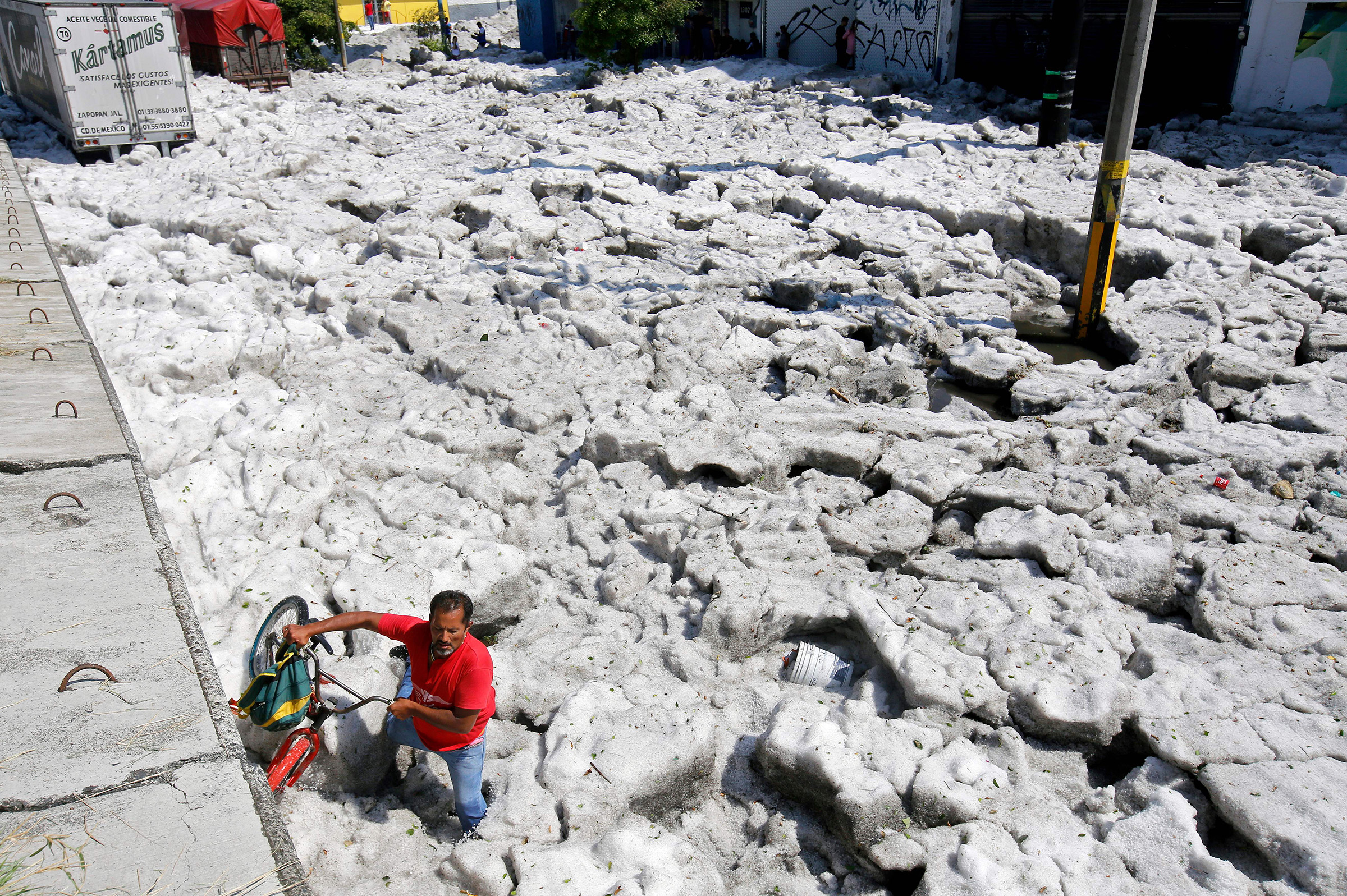 A man with a bike walks on hail in the eastern area of Guadalajara, Jalisco state, Mexico, on June 30, 2019. (Ulises Ruiz—AFP/Getty Images)