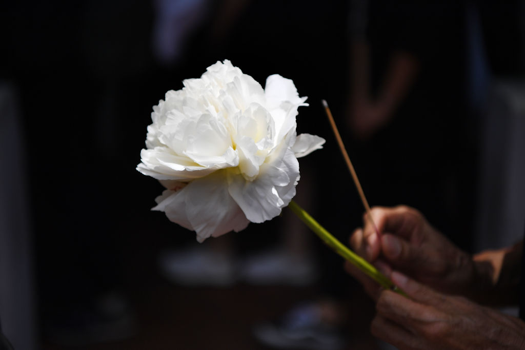 A mourner holds a flower and a incense stick to be placed at the site where a protester died in Hong Kong. (ANTHONY WALLACE&mdash;AFP/Getty Images)