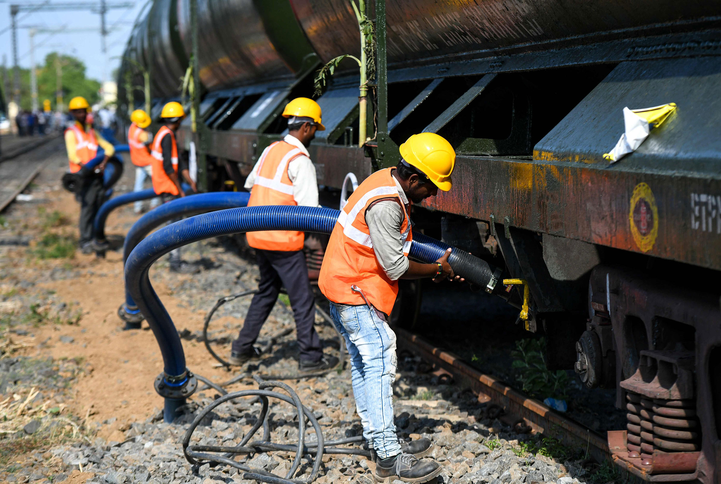 Indian laborers connect pipes to collect water from a train carrying liters of water at a railway station in Chennai on July 12.
