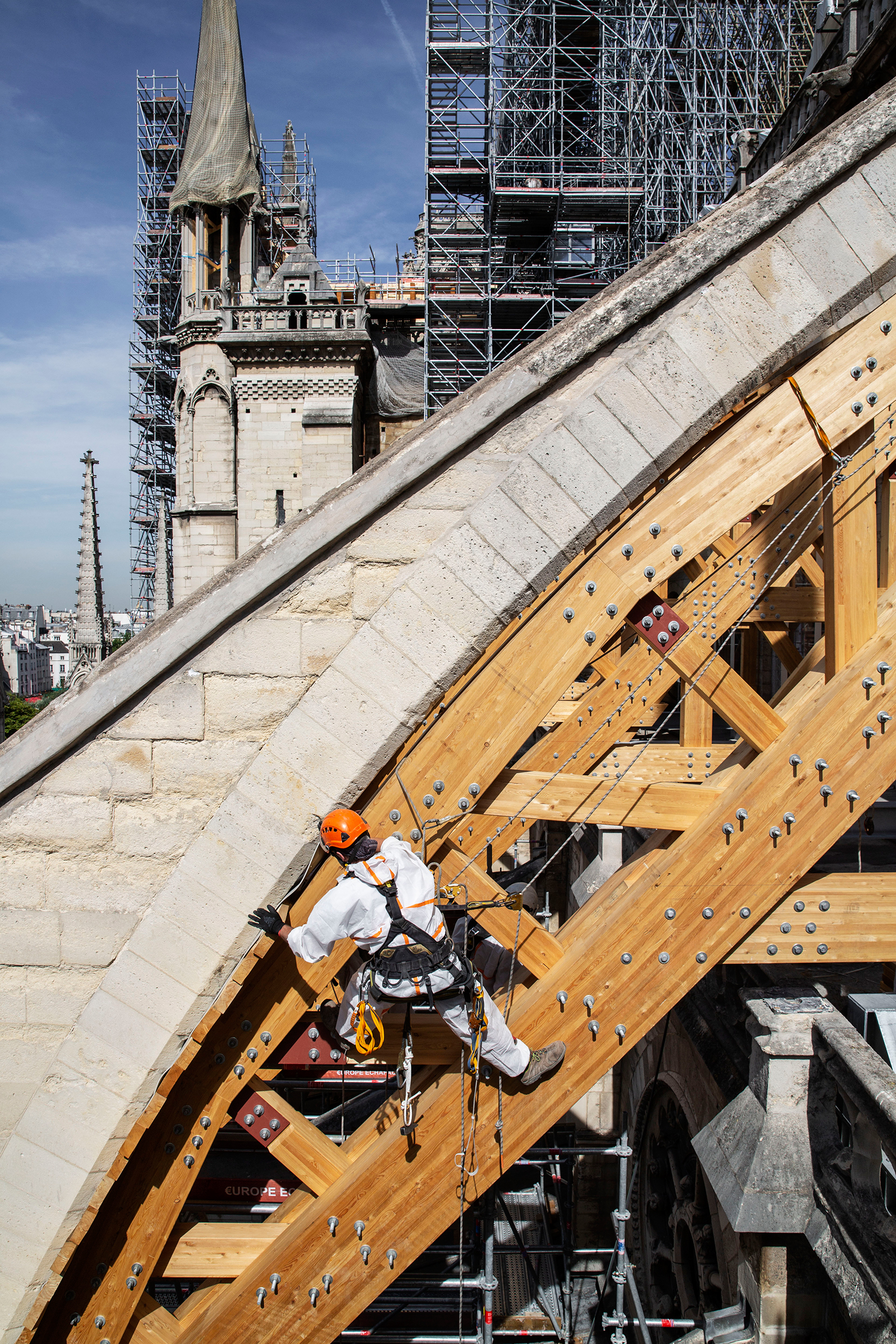 A rope-access technician installs a wooden arch to support a flying buttress on JulyÊ22, 2019.