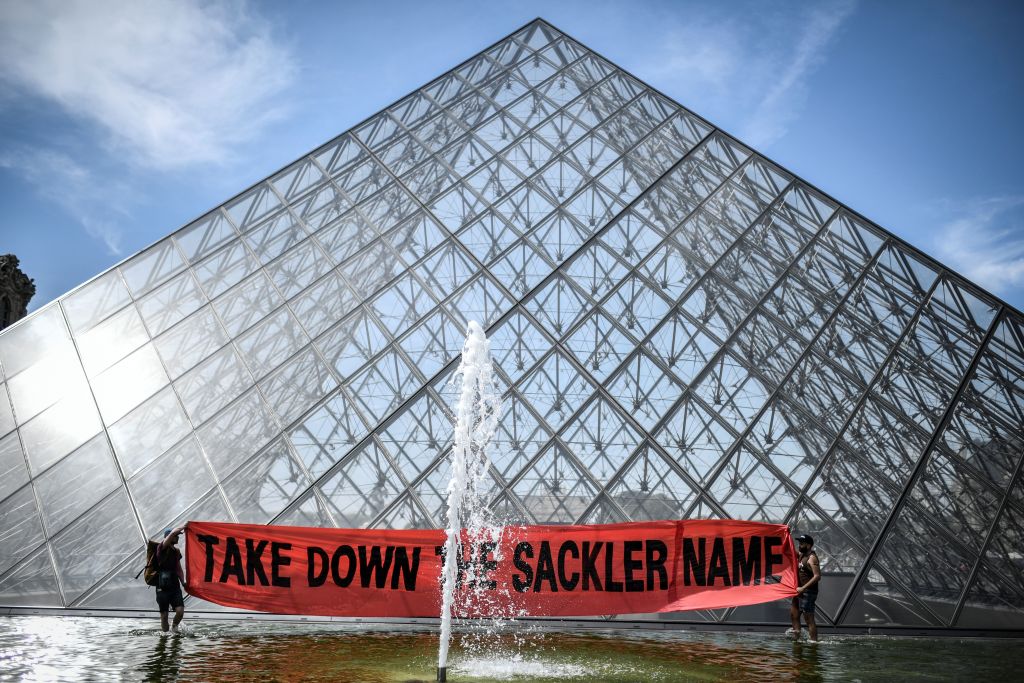 Activists hold a banner reading "Take down the Sackler name" in front of the Pyramid of the Louvre museum in Paris on July 1, 2019. (Stephane de Sakutin&mdash;AFP/Getty Images)