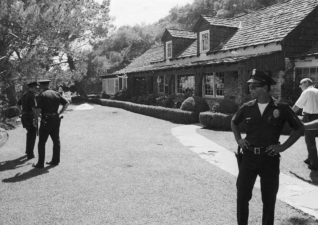 Police guard the rented estate of movie director Roman Polanski after his wife, actress Sharon Tate, and four other persons were found slain August 9th. Visible in the background is a shroud-covered body. (Bettmann—Bettmann Archive/Getty Images)