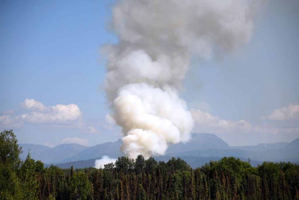 Smoke rises from a wildfire on July 3, 2019 south of Talkeetna, Alaska near the George Parks Highway. Alaska is bracing for a dangerous fire season with record warm temperatures and dry conditions in parts of the state. (Lance King—Getty Images)