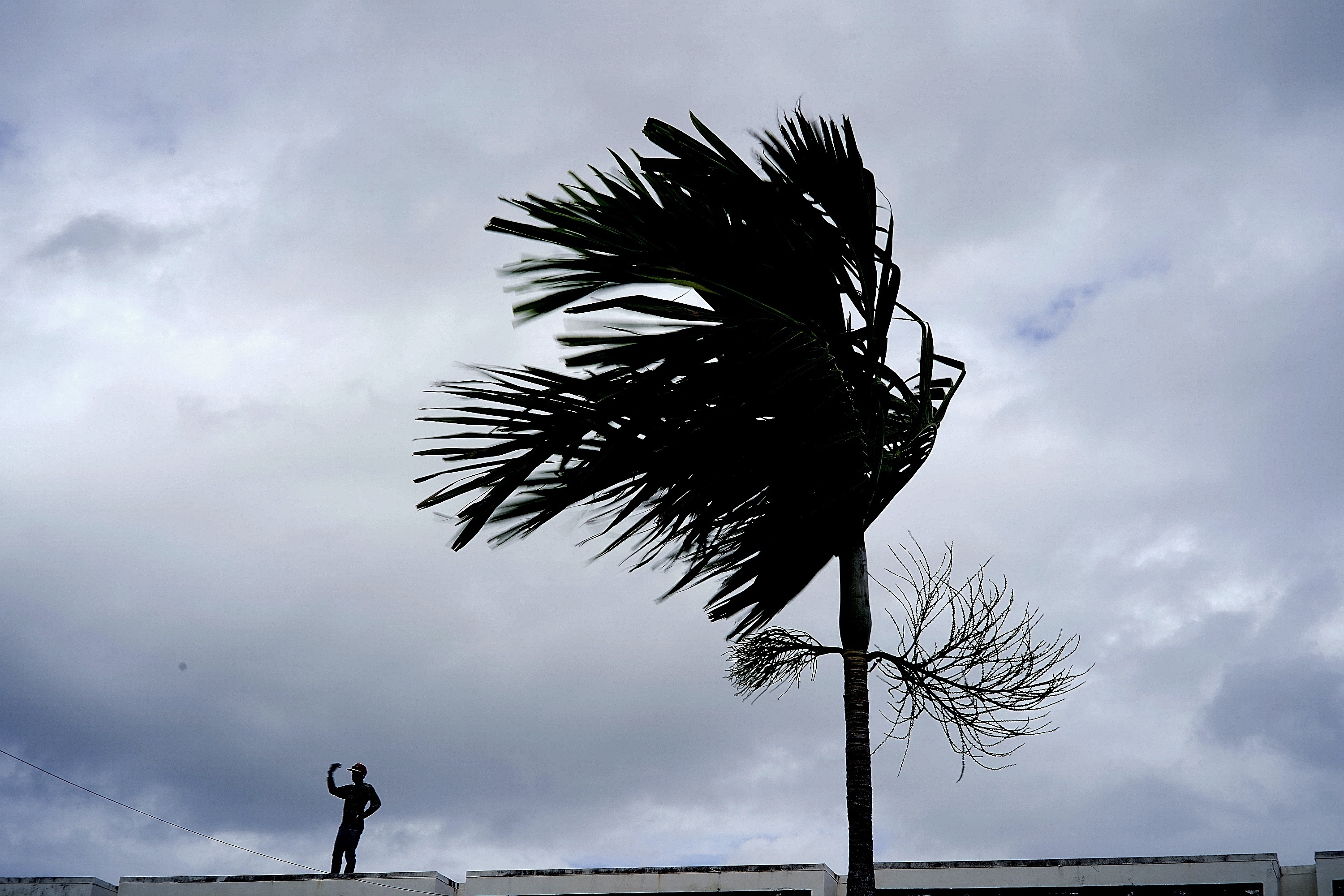 A man stands on a store's roof as he works to prepare it for the arrival of Hurricane Dorian in Freeport on Grand Bahama, Bahamas, Sunday, Sept. 1, 2019. (Ramon Espinosa—AP)