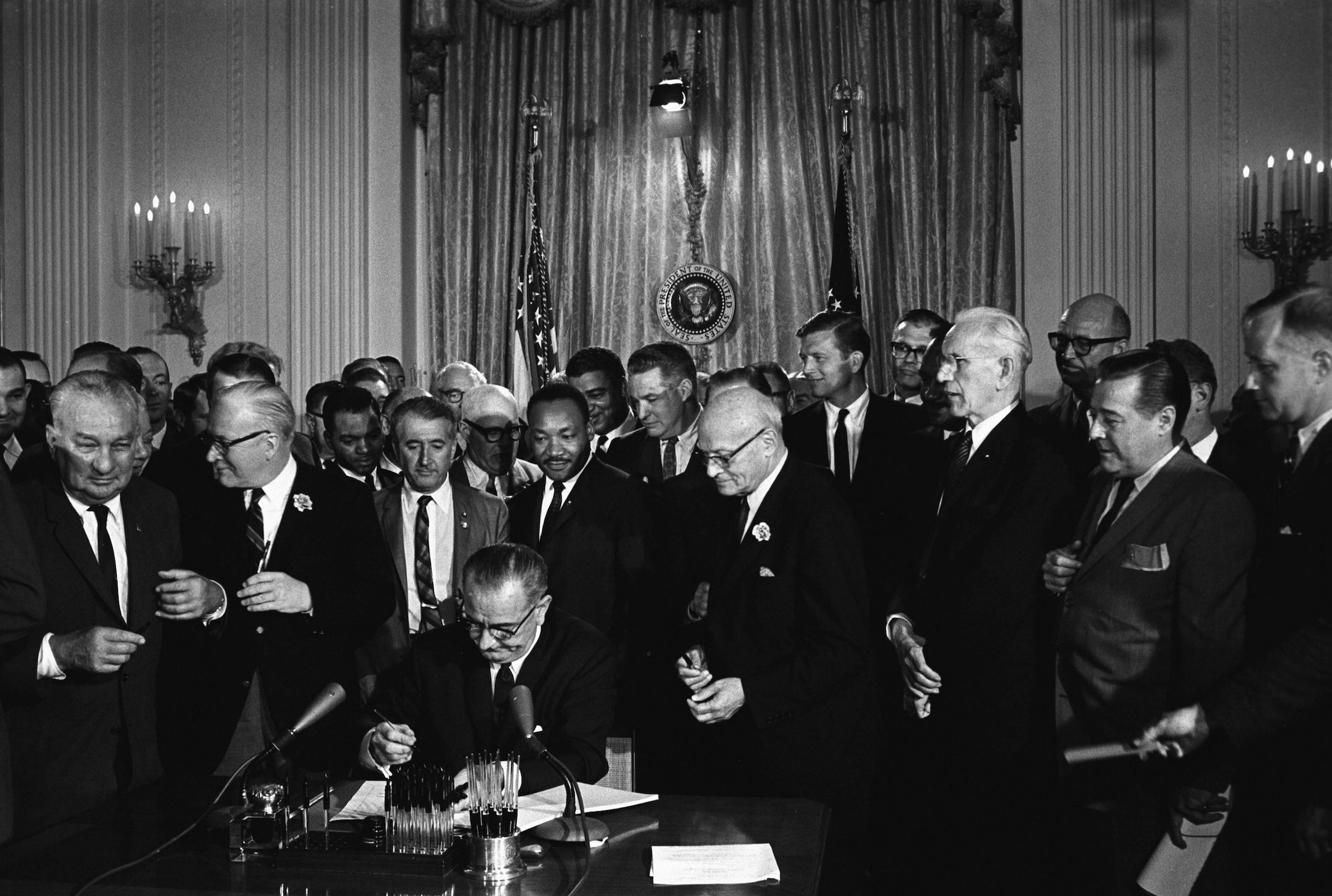 President Lyndon Johnson, seated, signing Civil Rights Act. Behind Johnson is Martin Luther King Jr. 1964. (Universal History Archive/Getty Imagse)